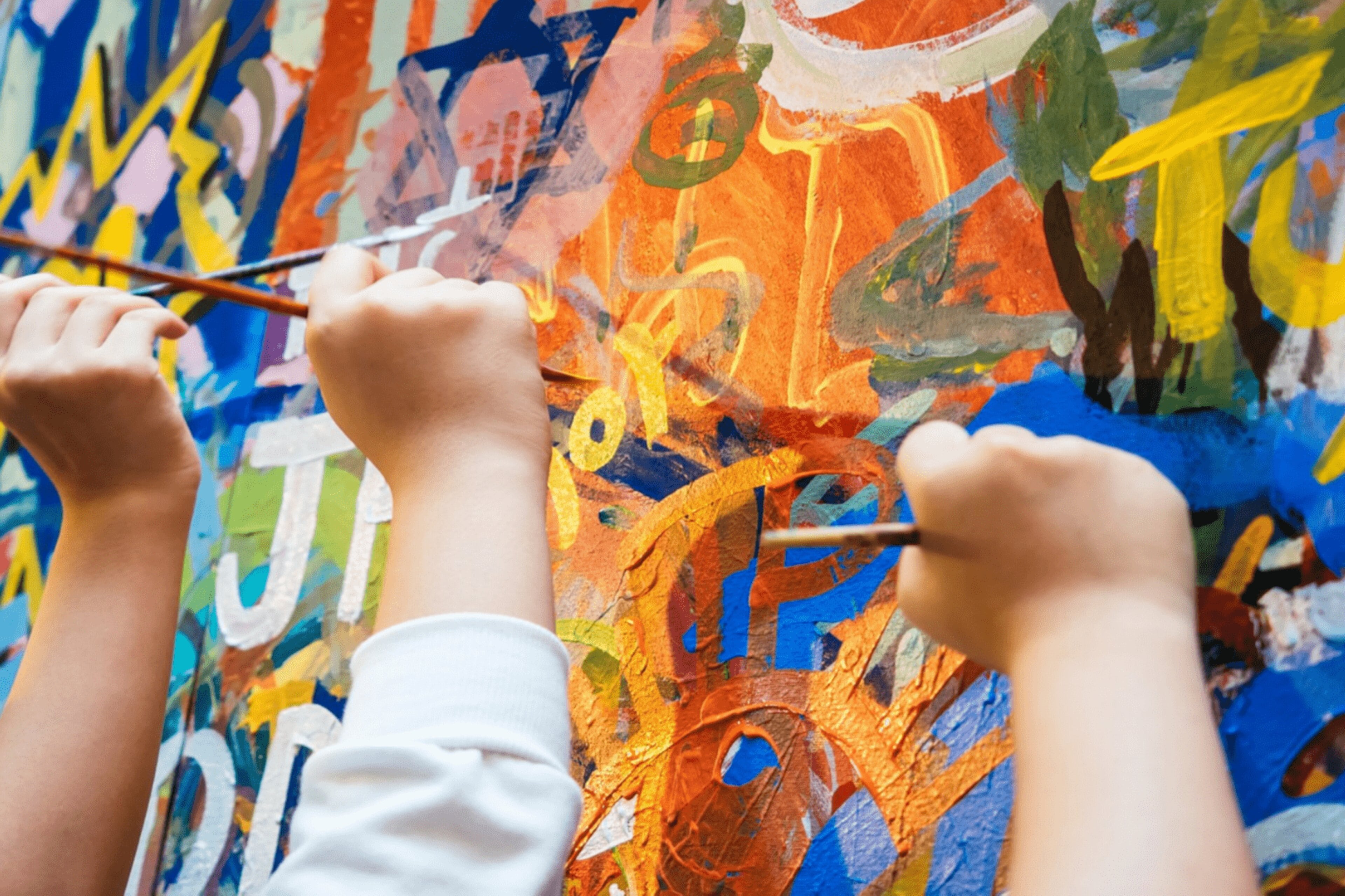 Children drawing on the wall using paint brushes