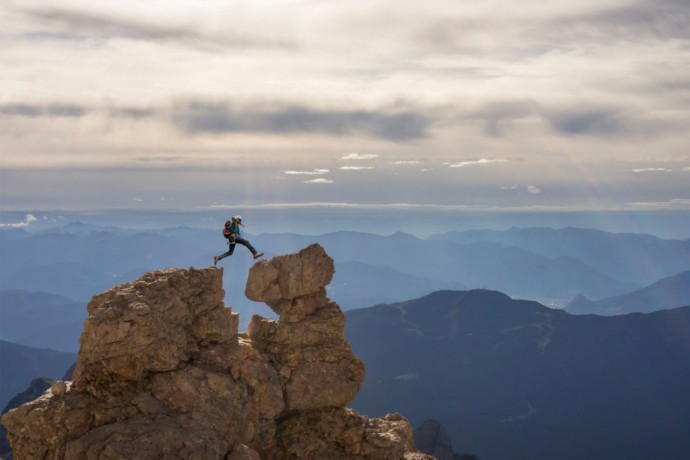  Men jumping from one rock to another rock in a mountain