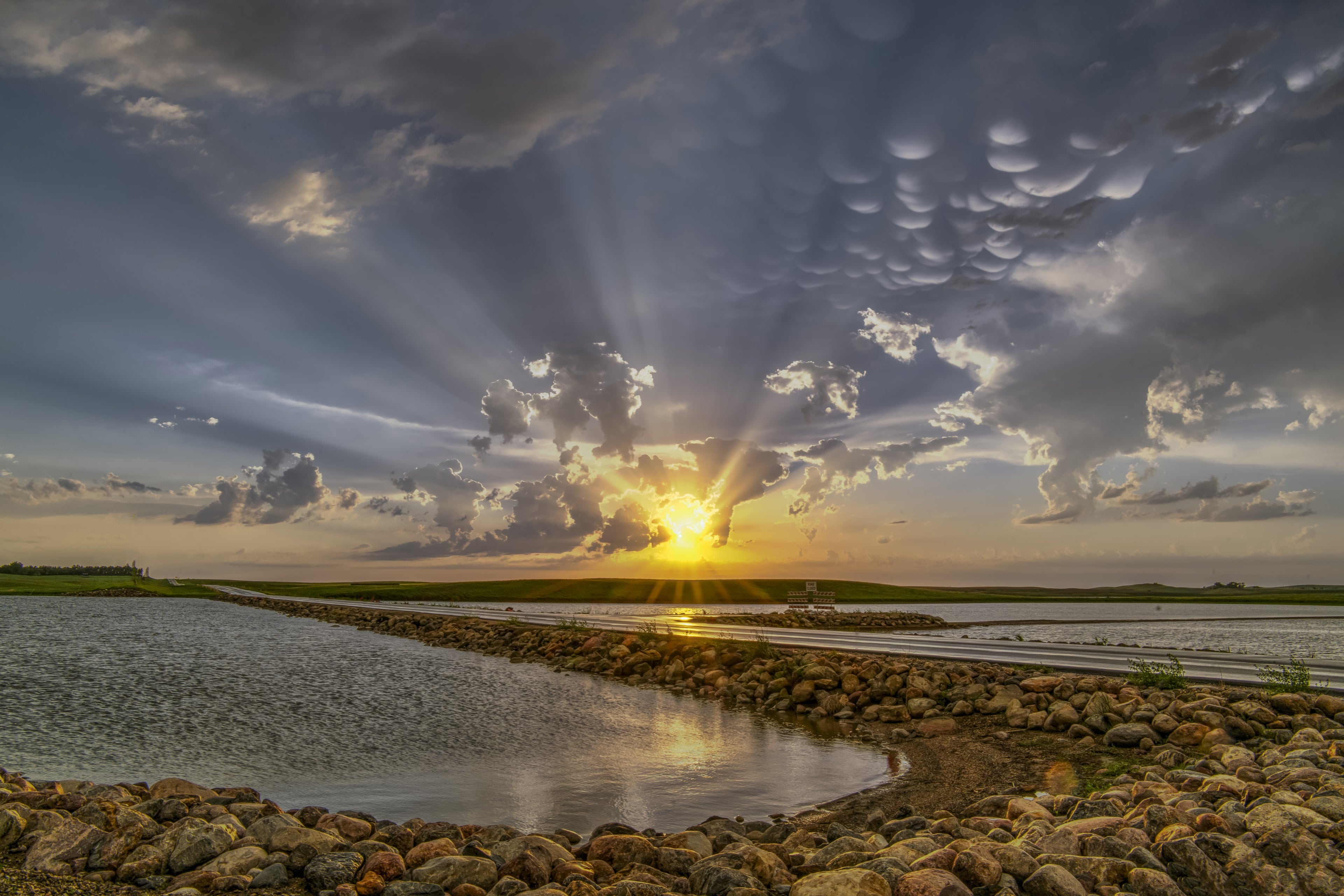 Rays of sunlight shining through clouds with shallow waters in the foreground