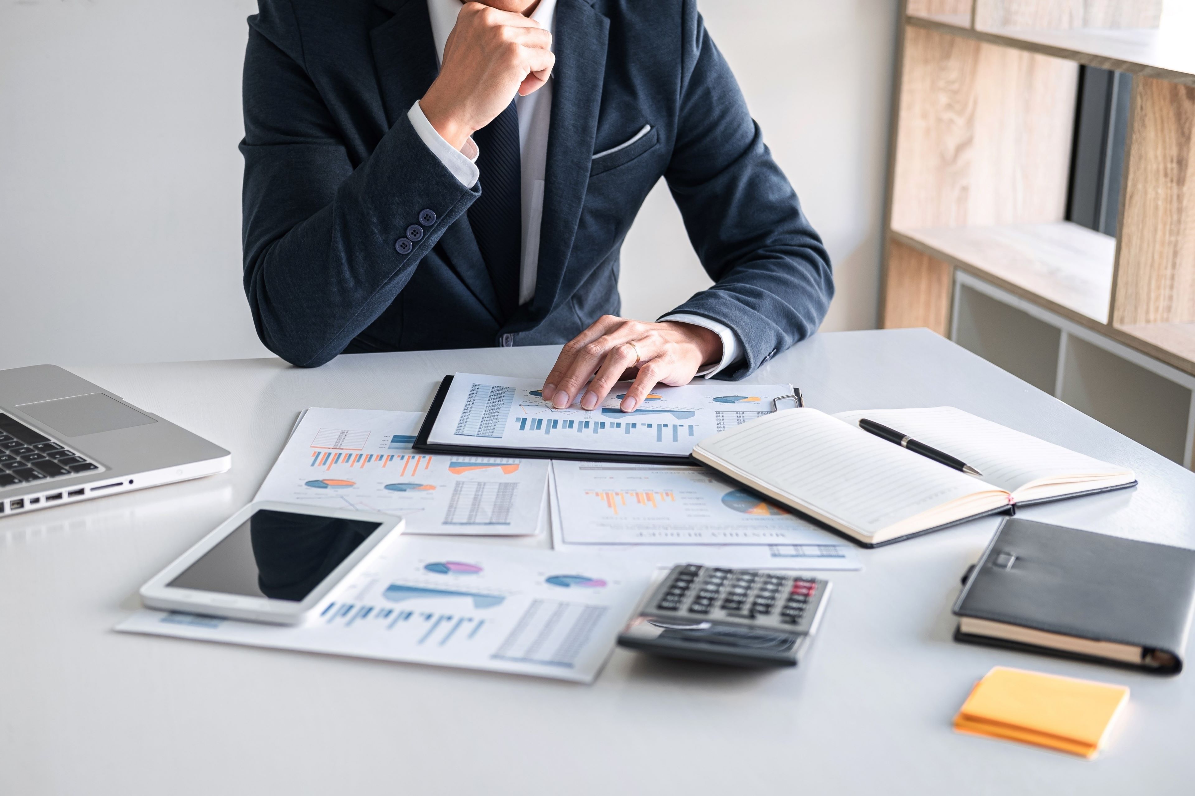 Man analyzing the statistics reports and placed calculator, tablet around the reports 