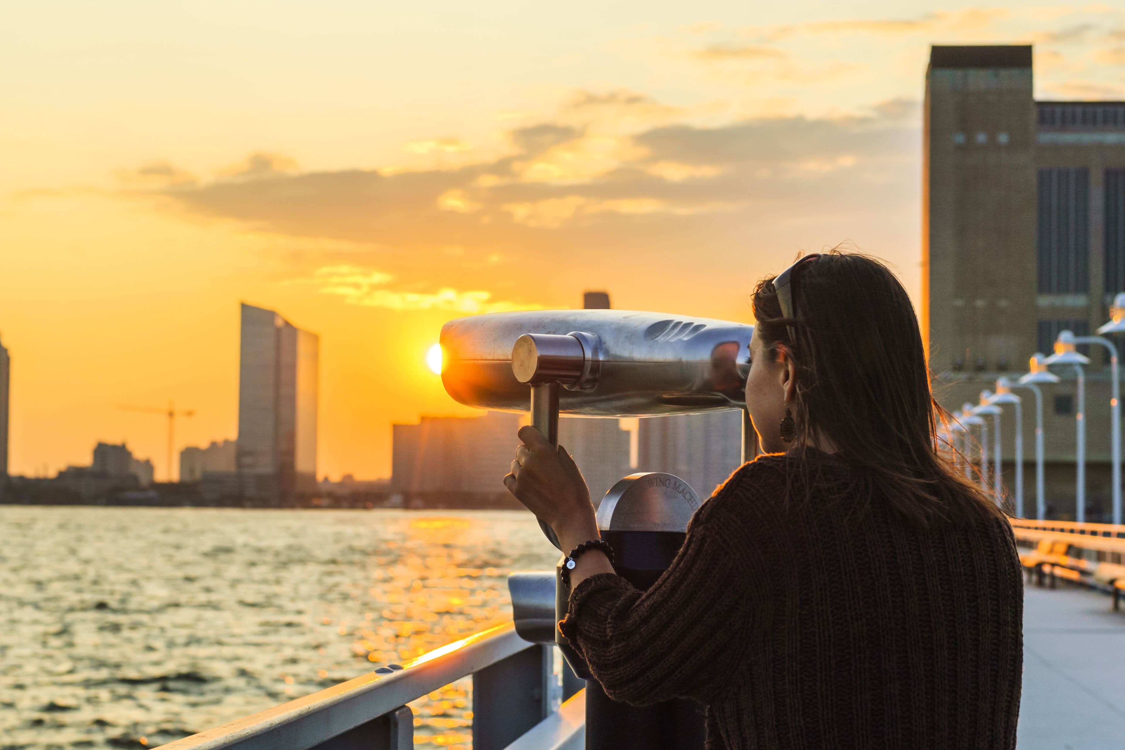 Young woman looking through coin-operated binocular