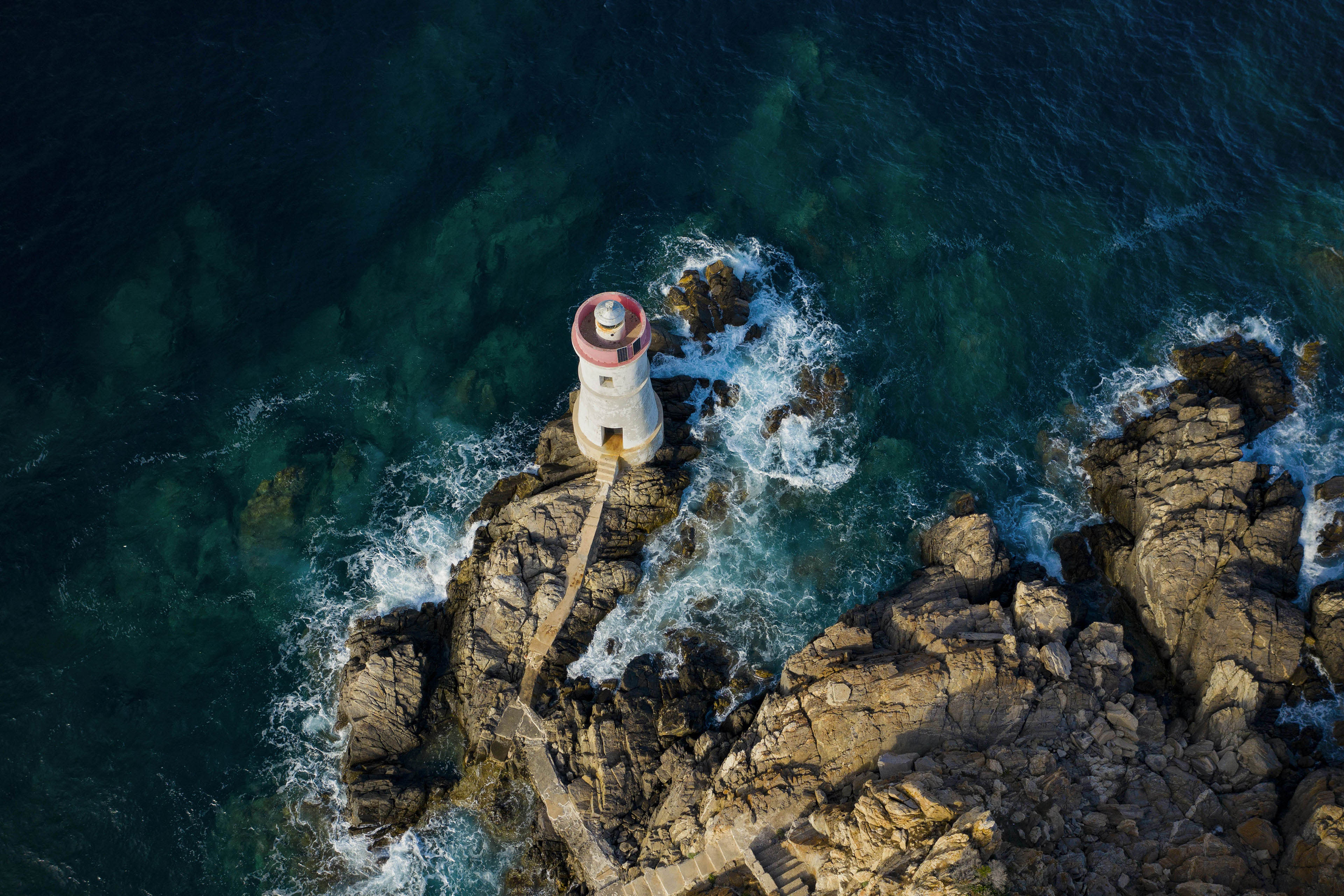 Aerial view of old lighthouse with rocky coast 