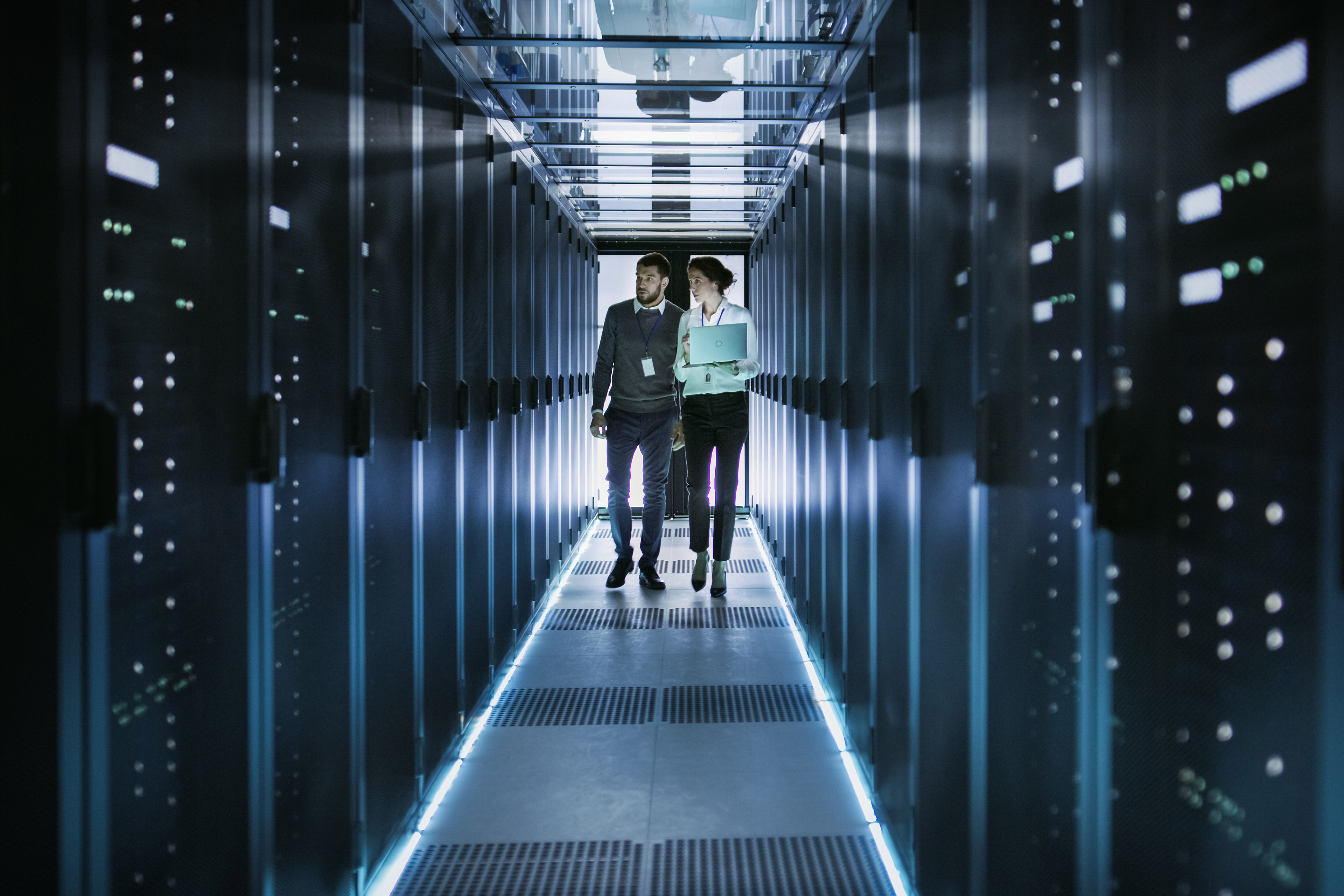 Man and woman walking in a space full of servers