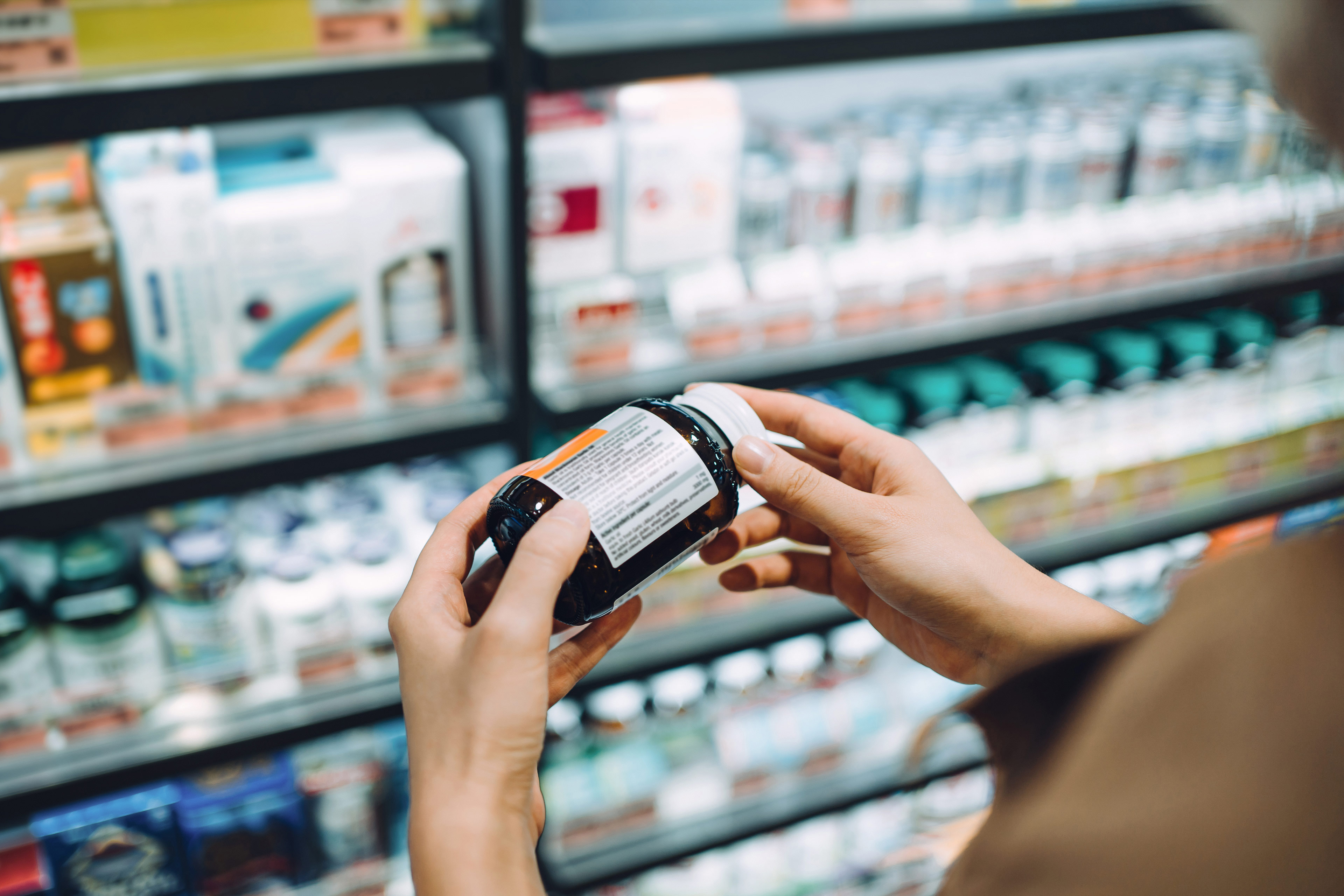  woman browsing through medical products and reading the label on a bottle of medicine 