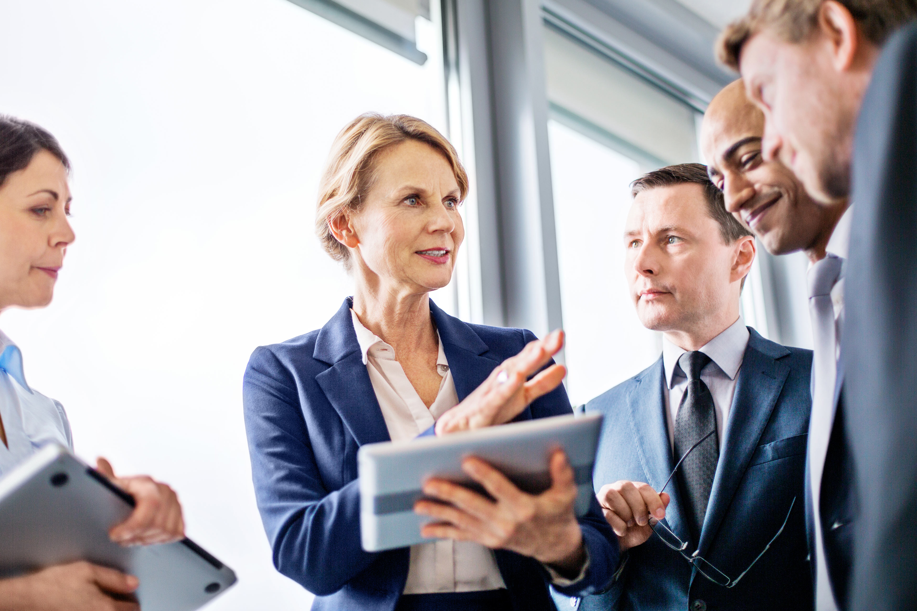 Mature businesswoman explaining new business ideas to colleagues during a standing meeting in office