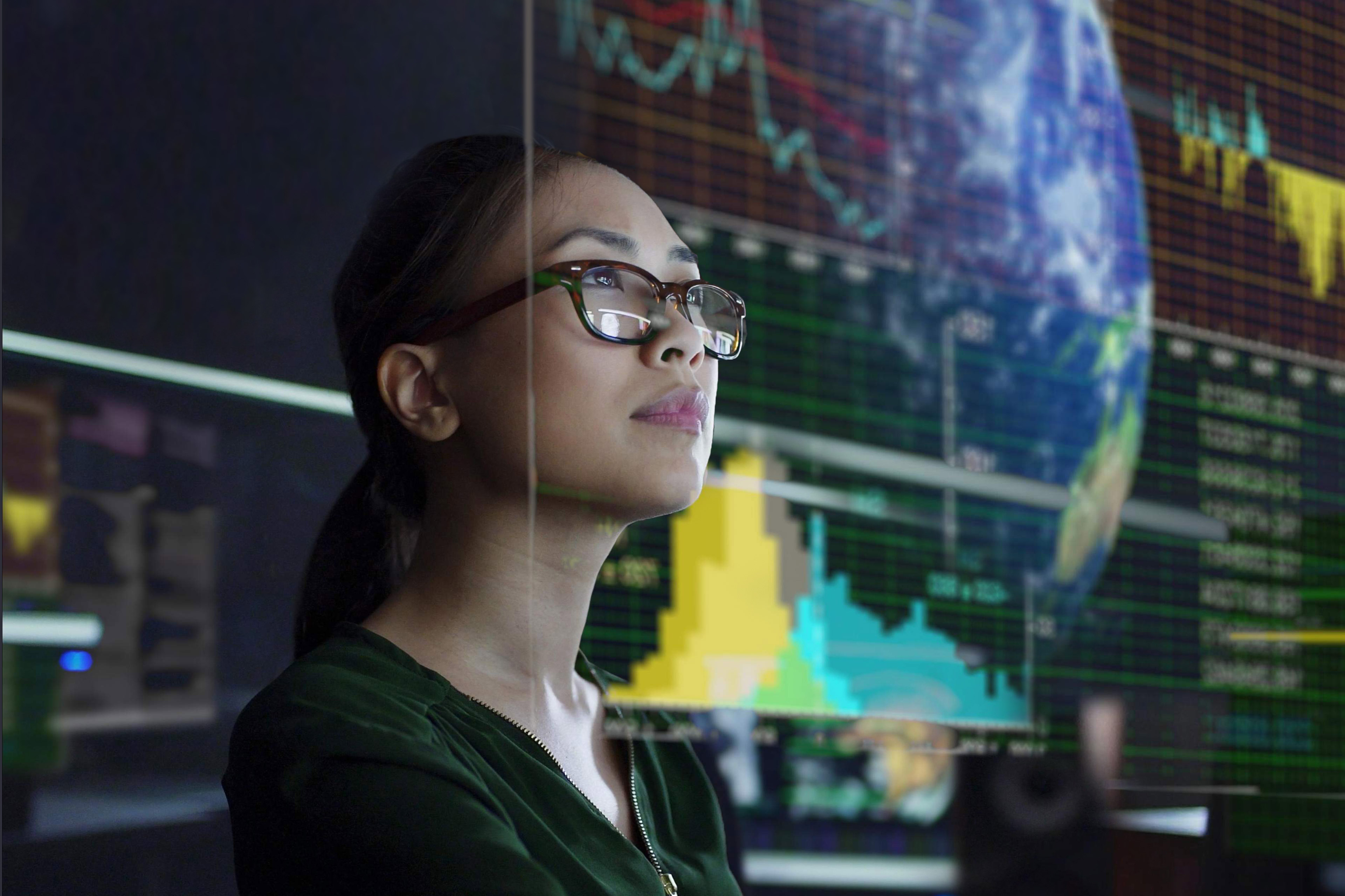 young Asian woman looking at environmental data in a dark office