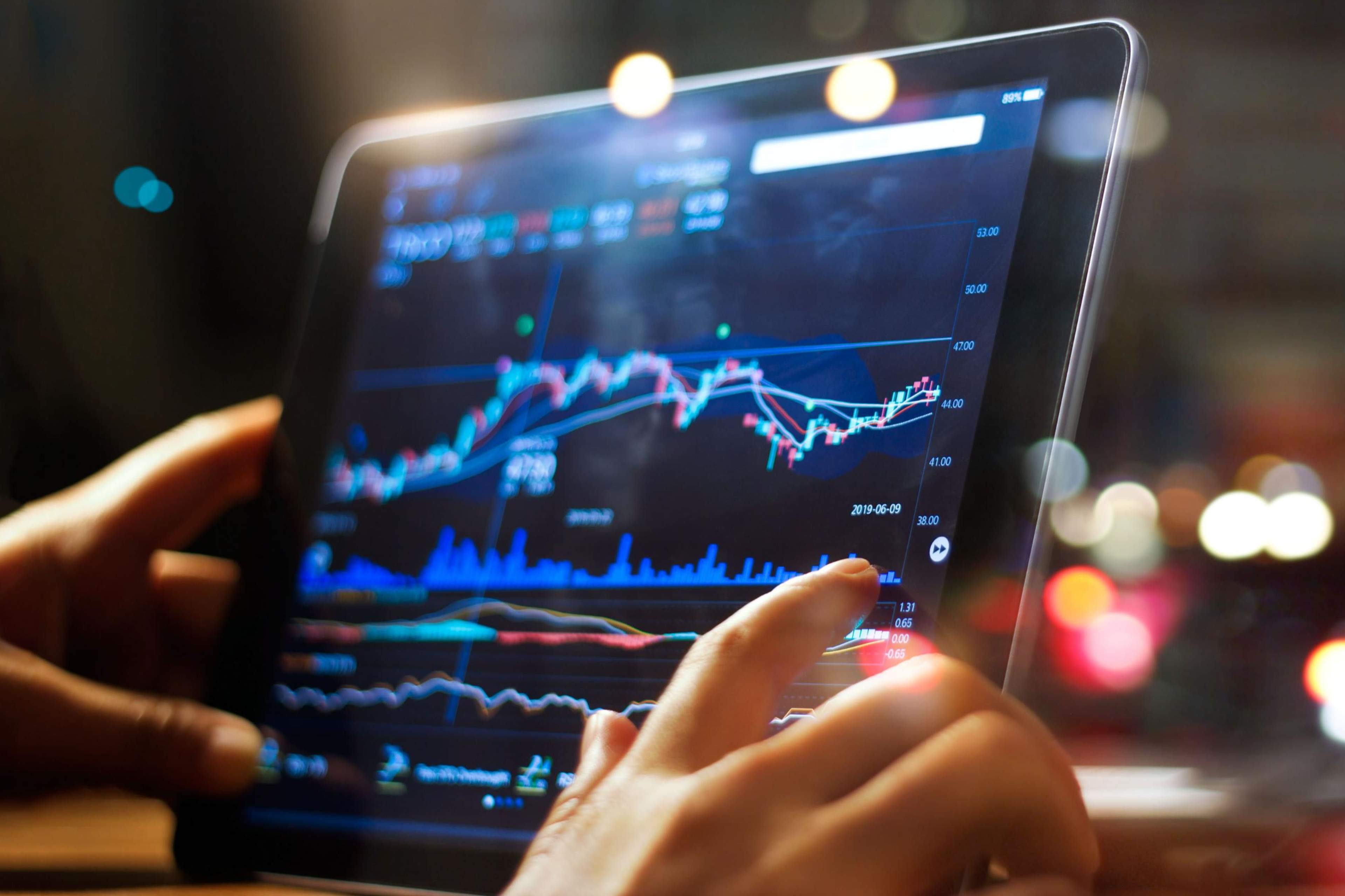 Businessperson checking stock market data on tablet at night