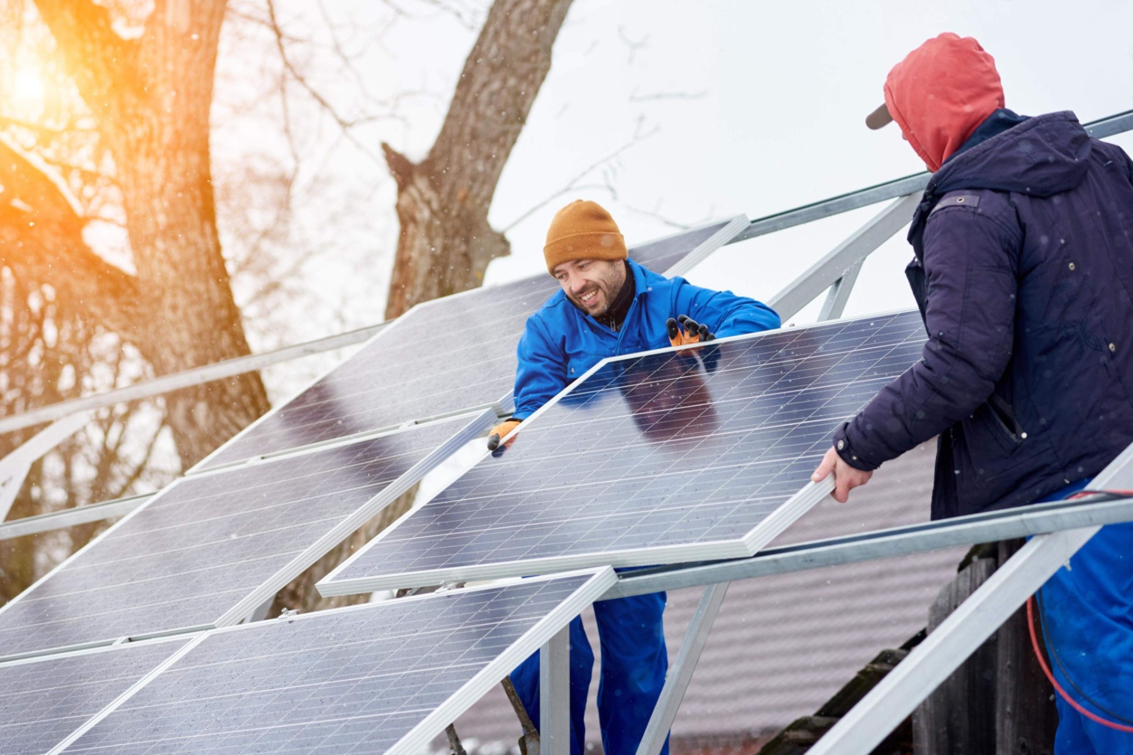 Technicians mounting blue solar modules on roof of modern house