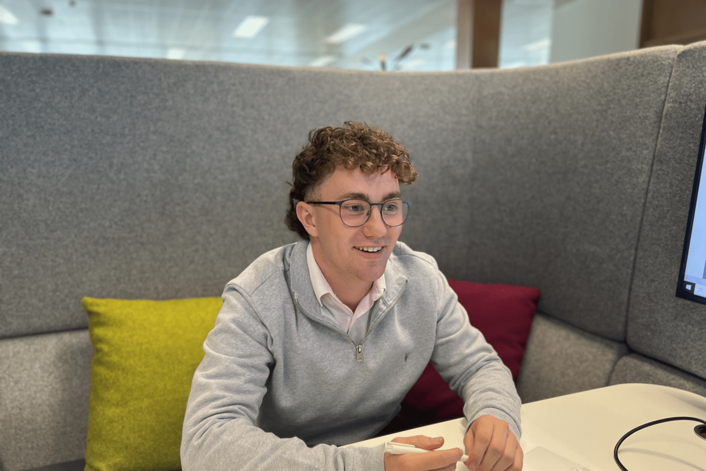 The person wearing glasses and sitting in the office couch