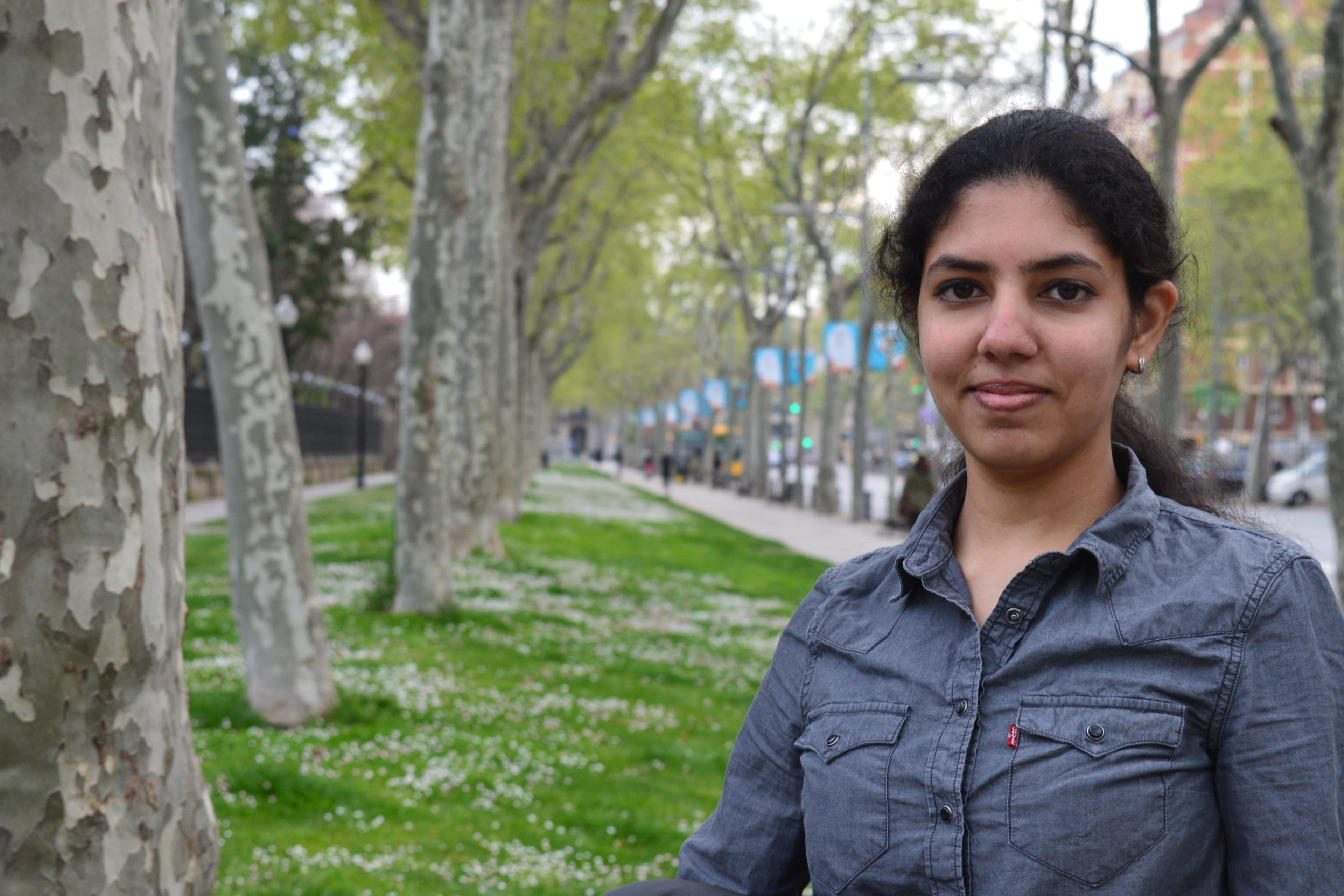 A woman standing beside the road under a tree.