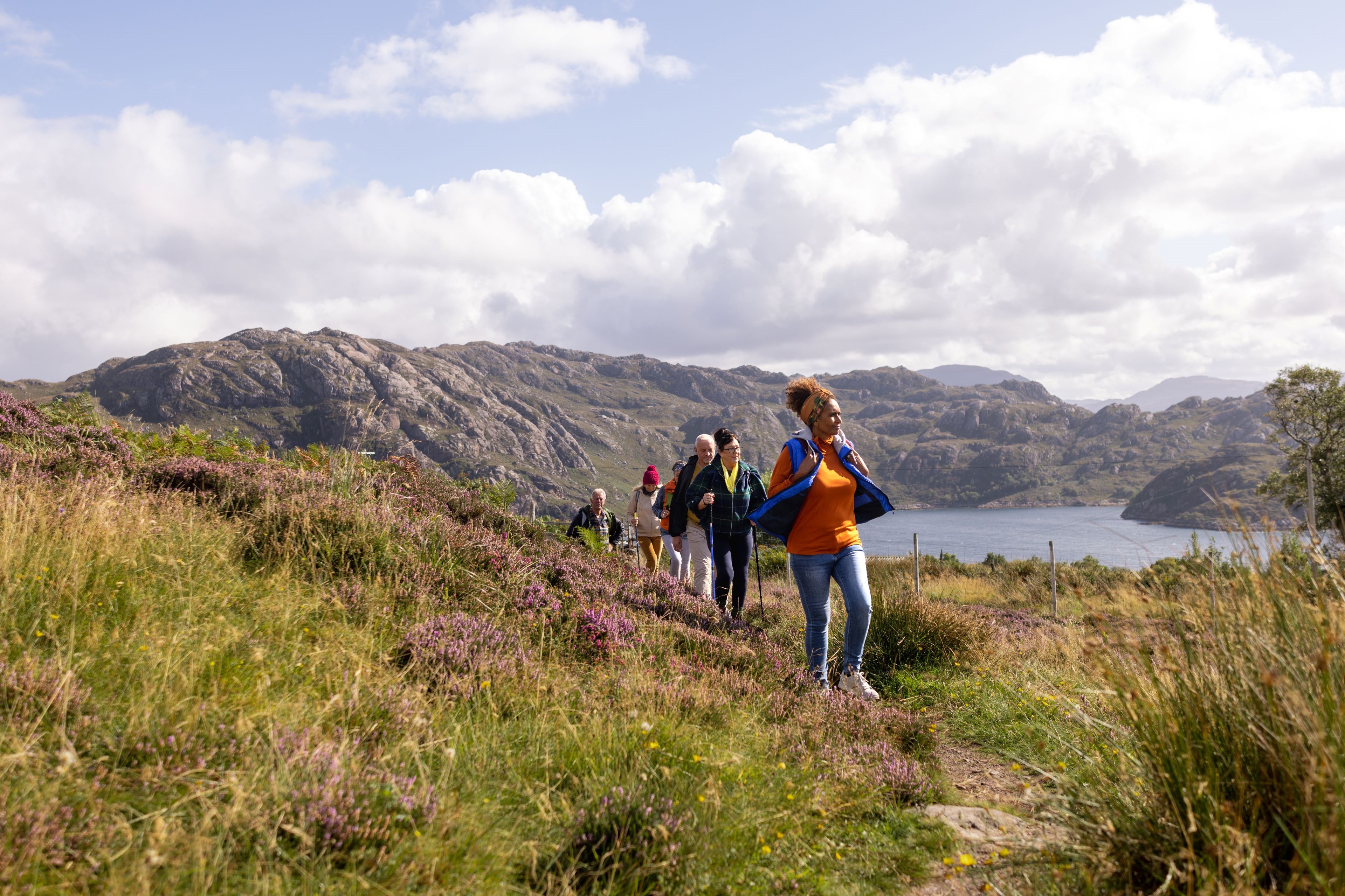 Landscape photograph of a woman leading a hike through hills with a lake in the background