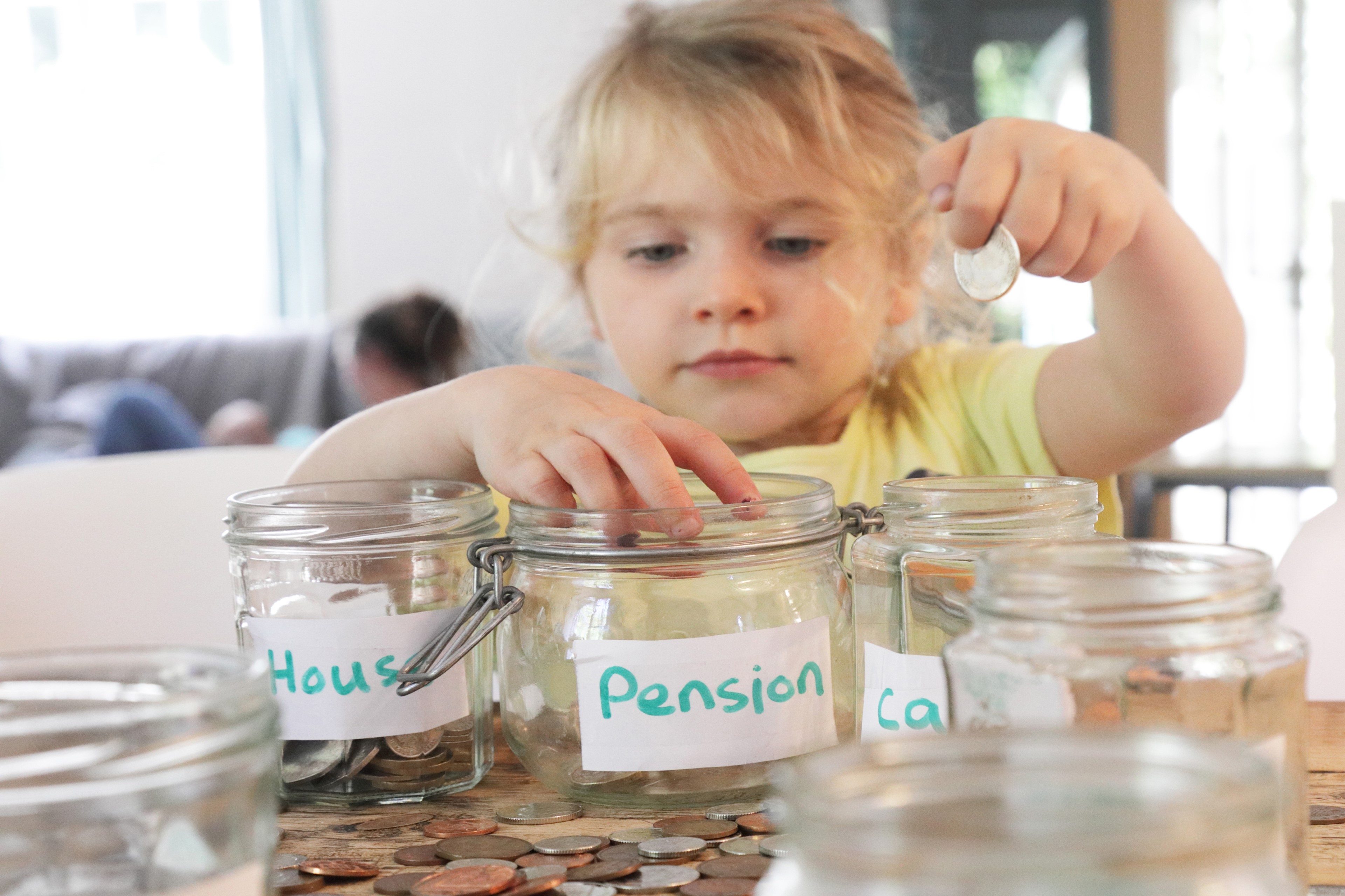 Young girl putting money into jar