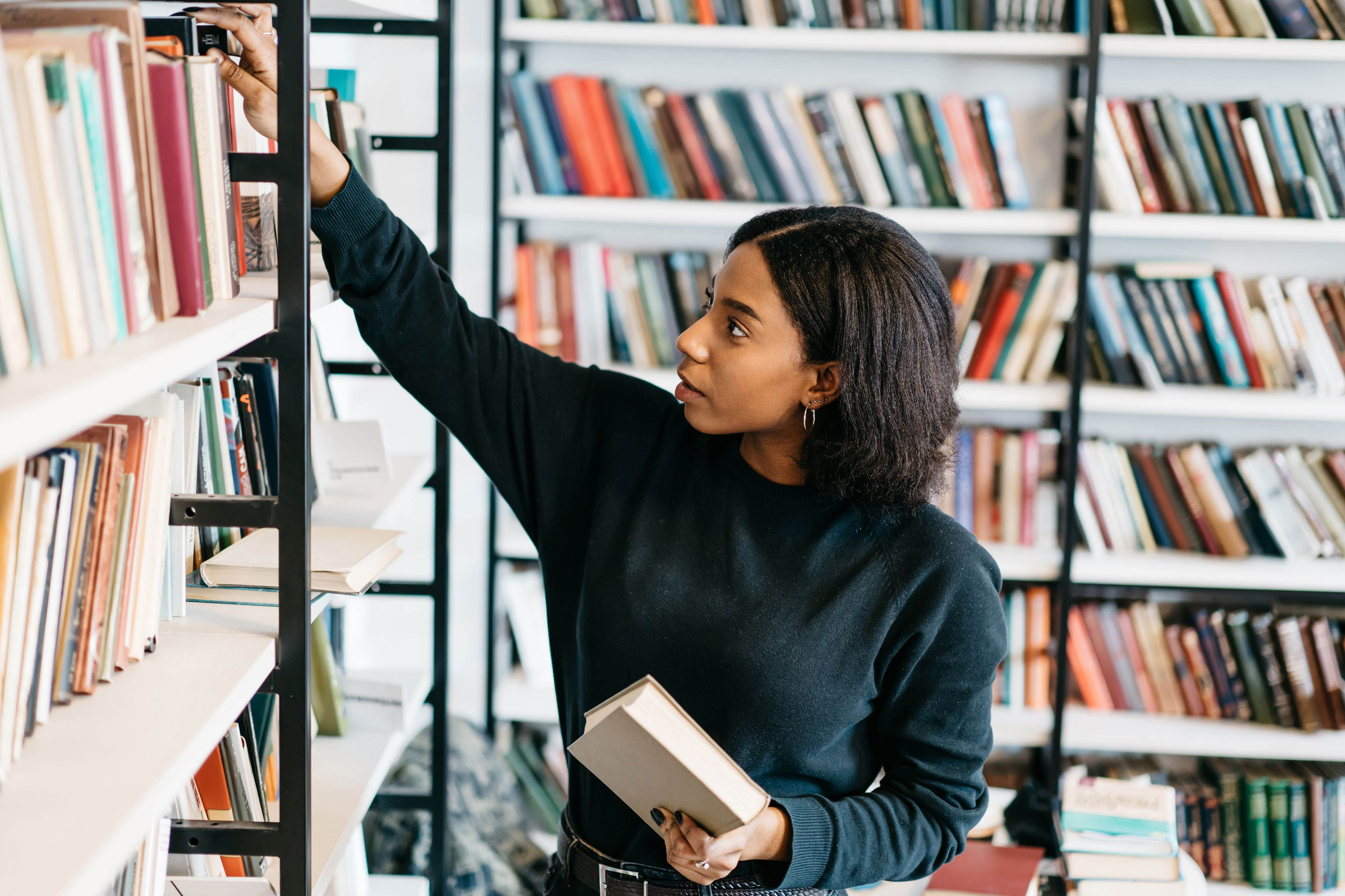 Female african american pulling a book from a bookshelf