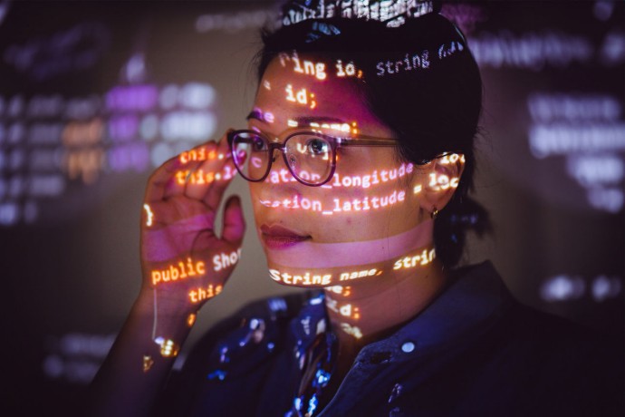Female programmer with program code projected on her face