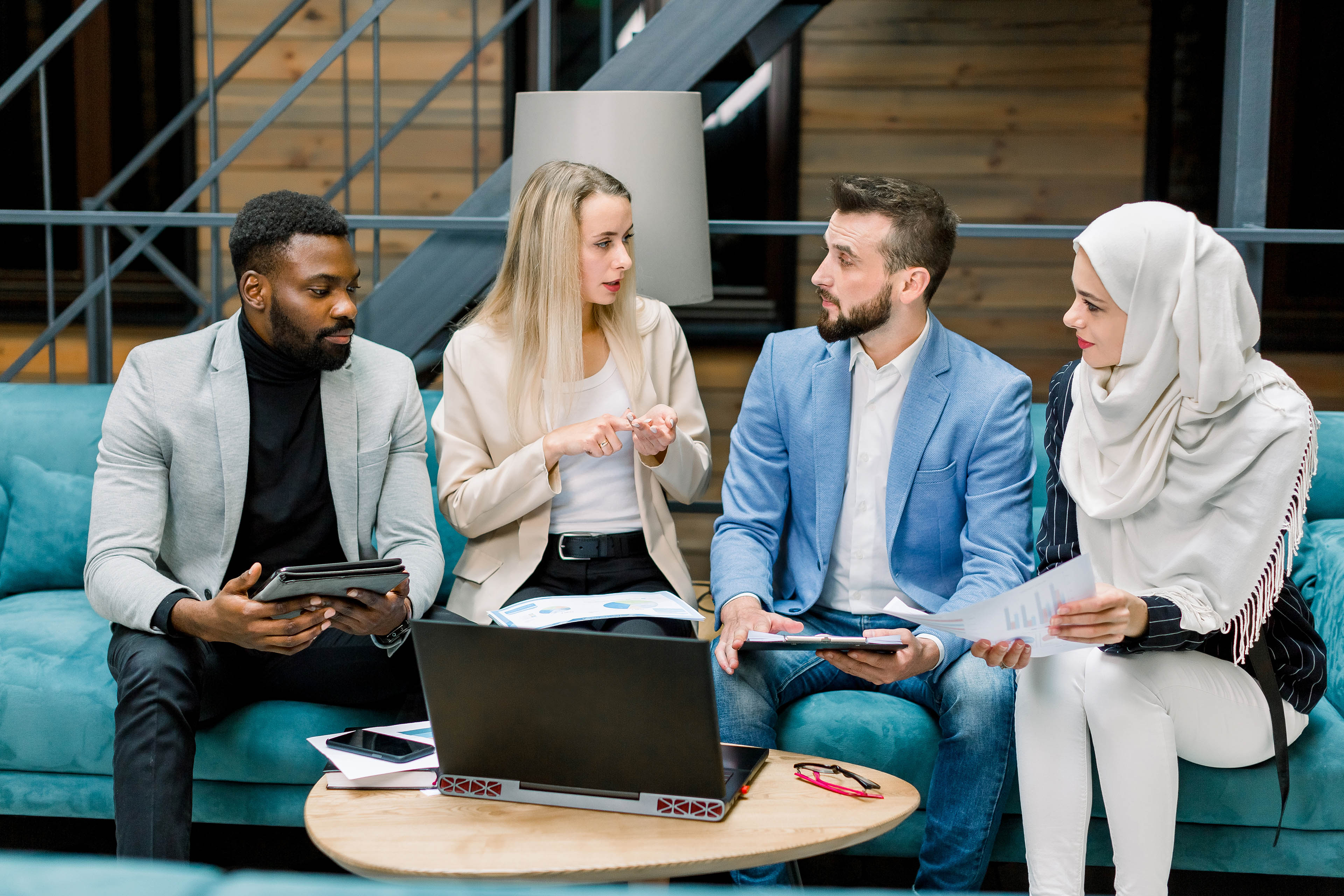 Focused multi ethnic businesswomen and businessmen discussing their joint business project in the modern office room