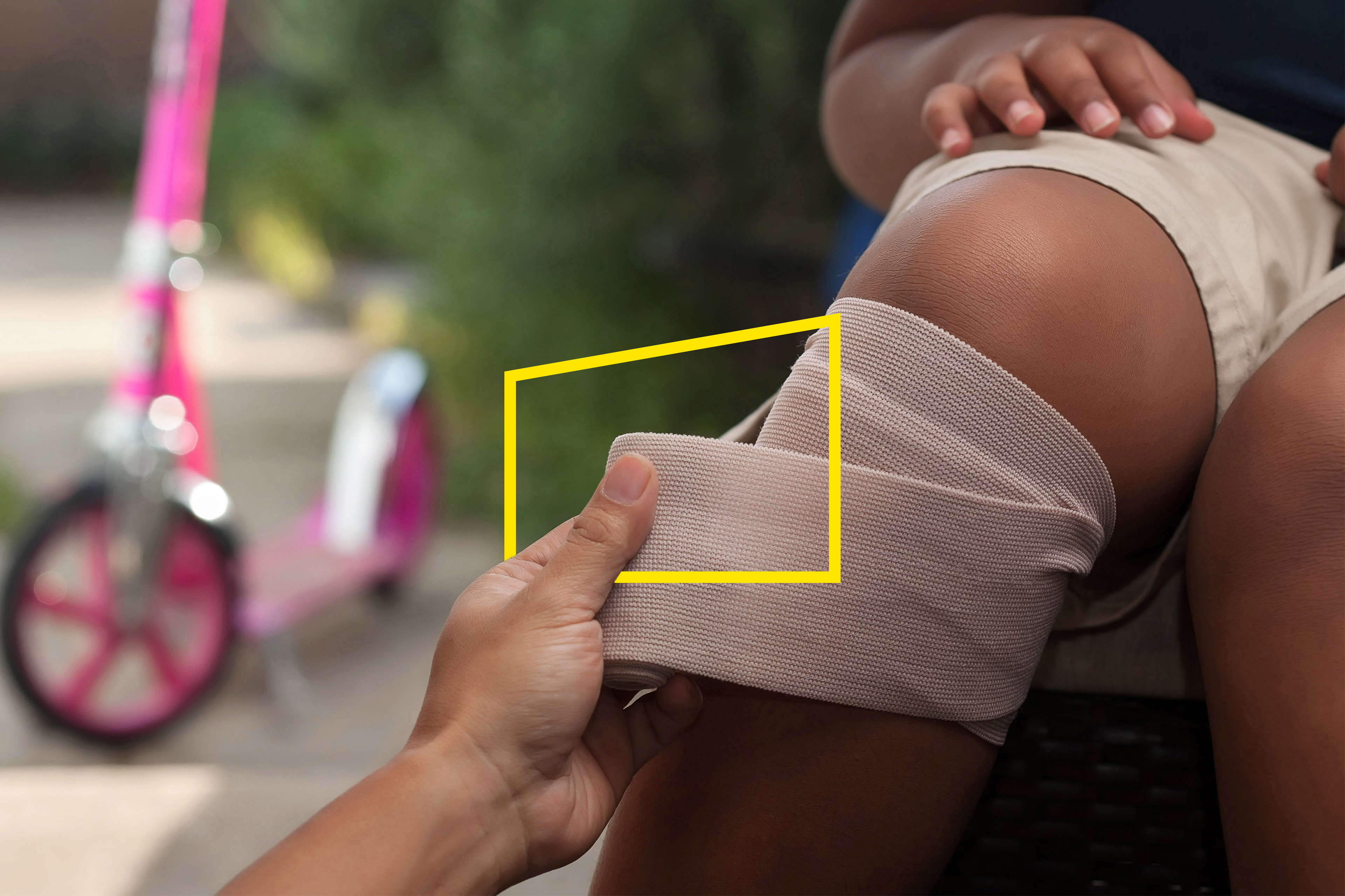 A young girl getting her knee wrapped with a bandage