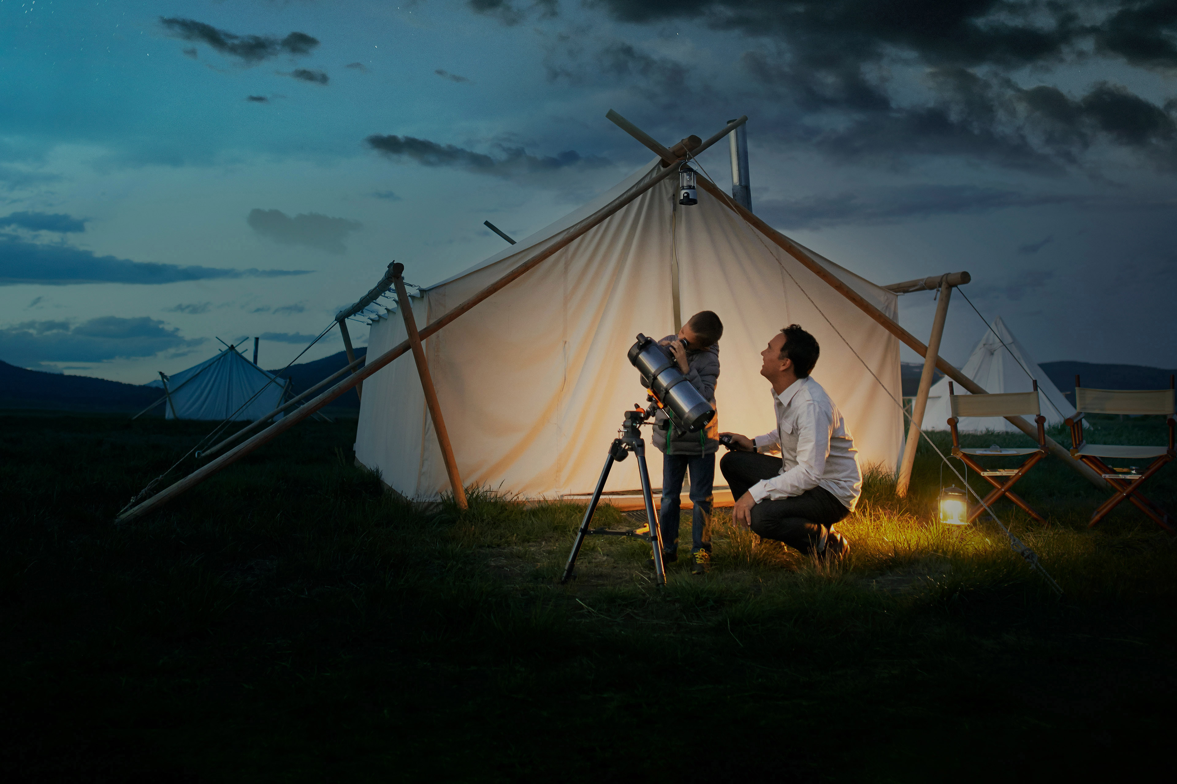 Father and son watching stars through telescope in the night