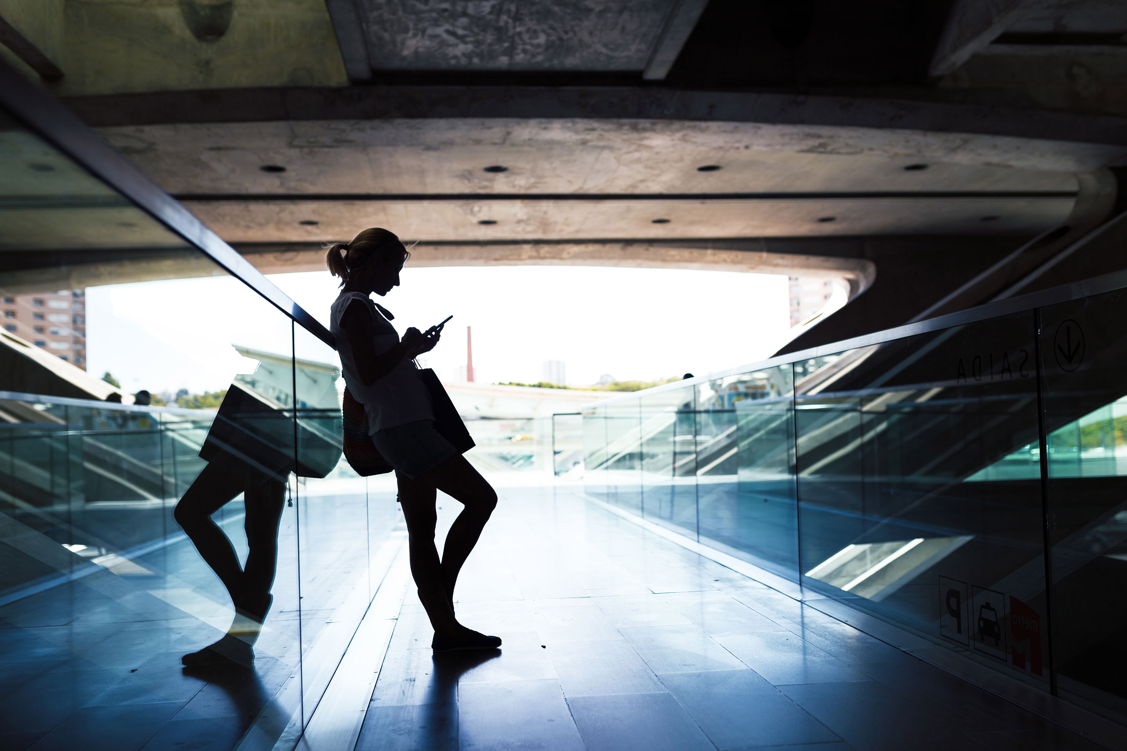 Young woman standing against the glass on phone