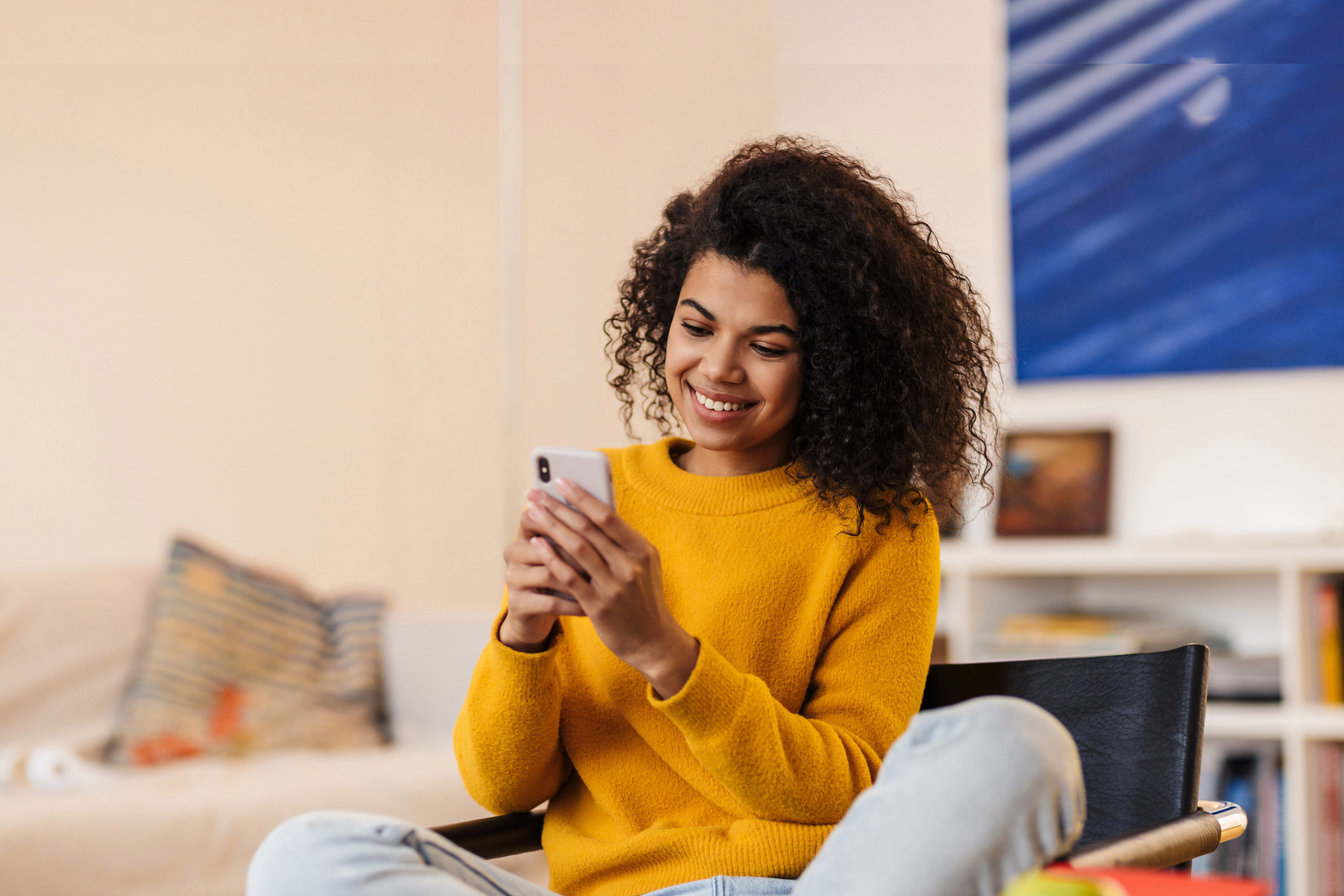 African American woman using cellphone while sitting on chair