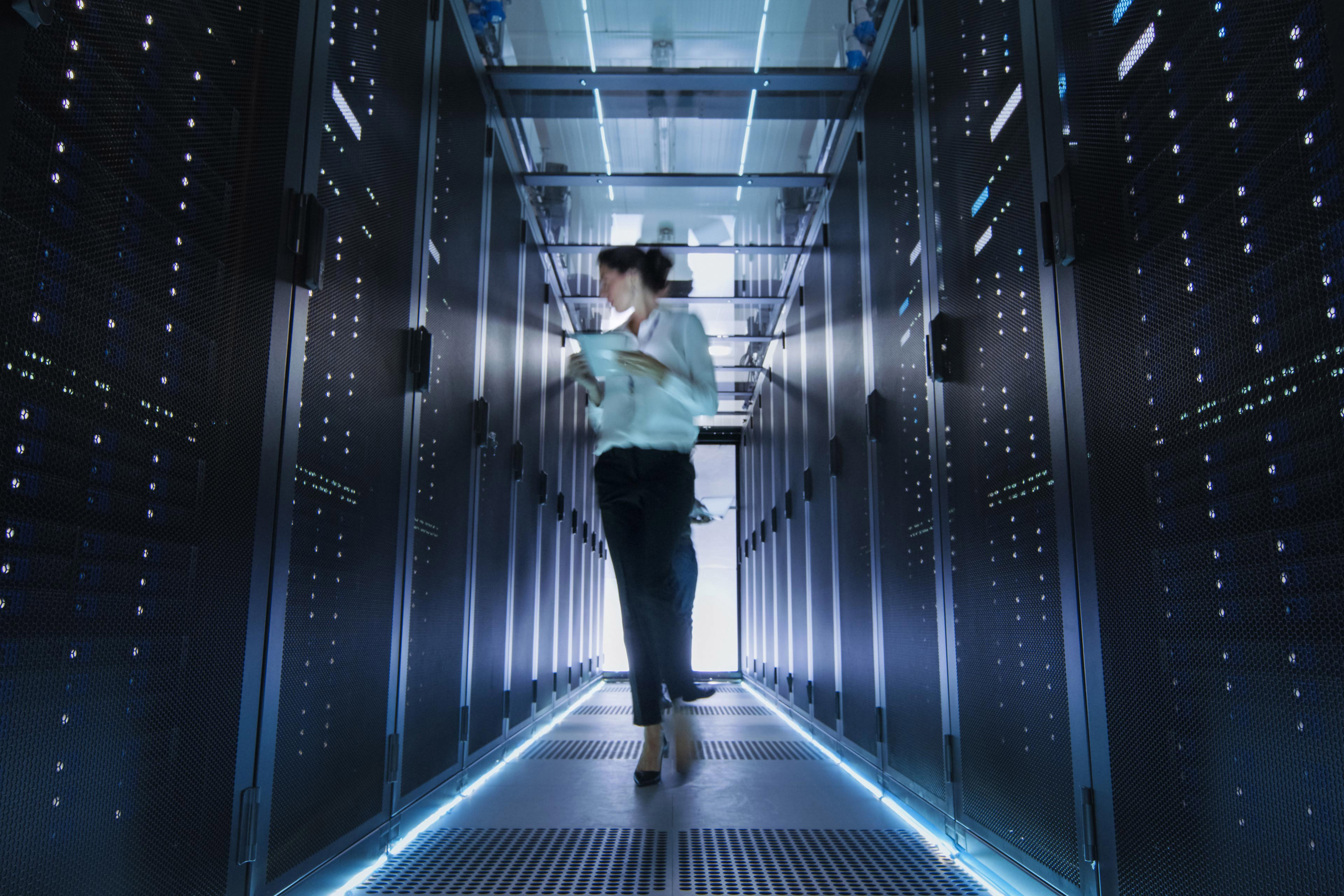 Female IT engineer walking in data center holding tablet