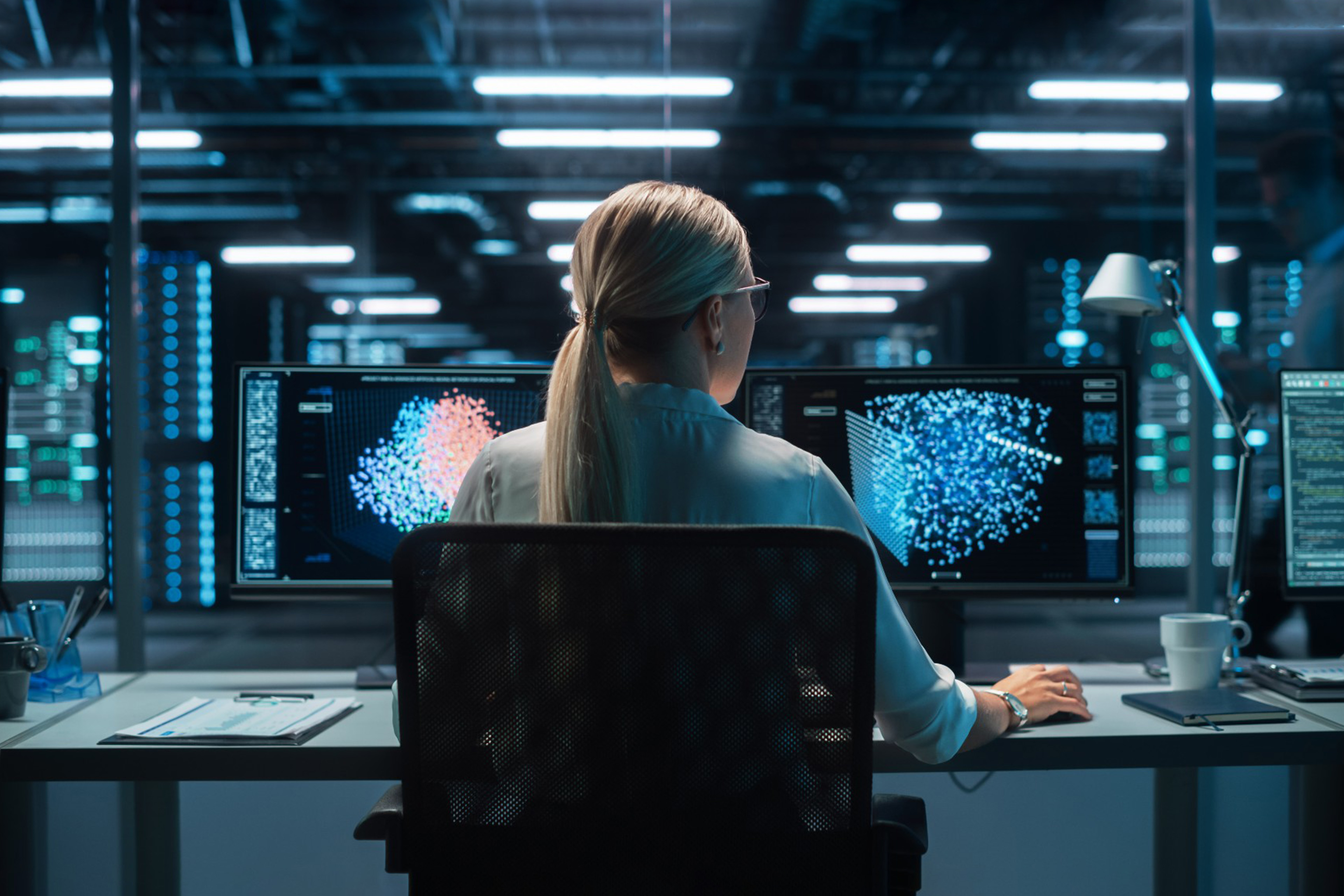 Female Computer Engineer Looking on the Two Displays while Working on the Computer