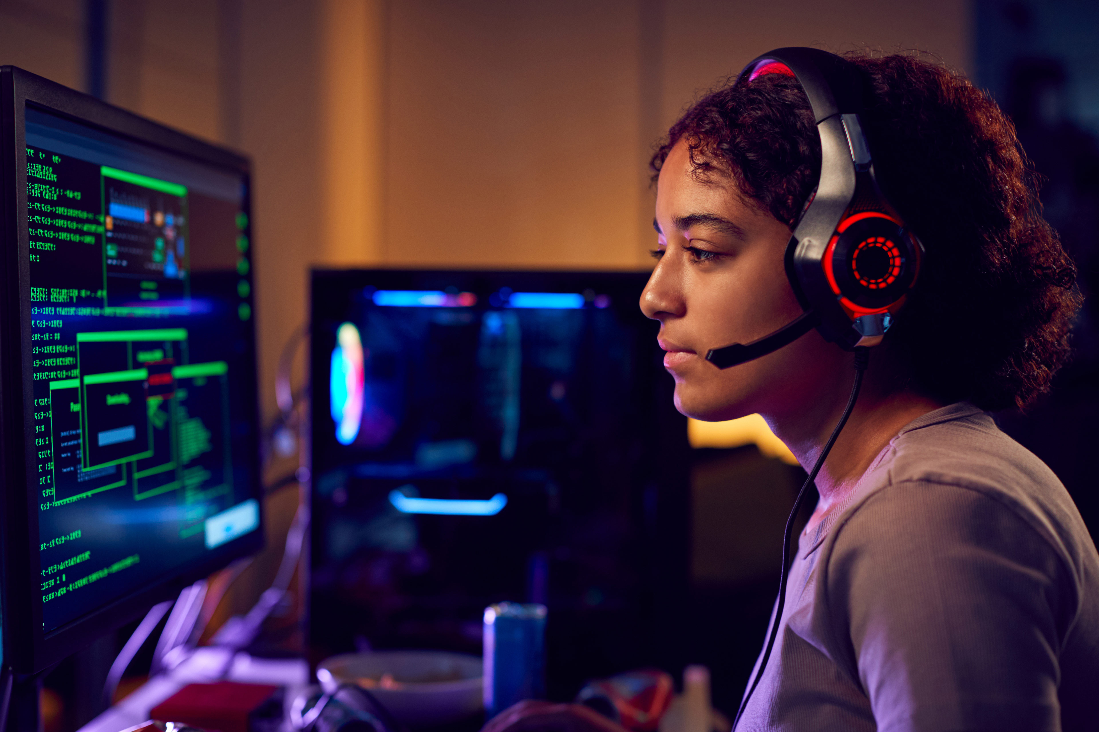 Female teenage hacker sitting in front of computer screens bypassing cyber security