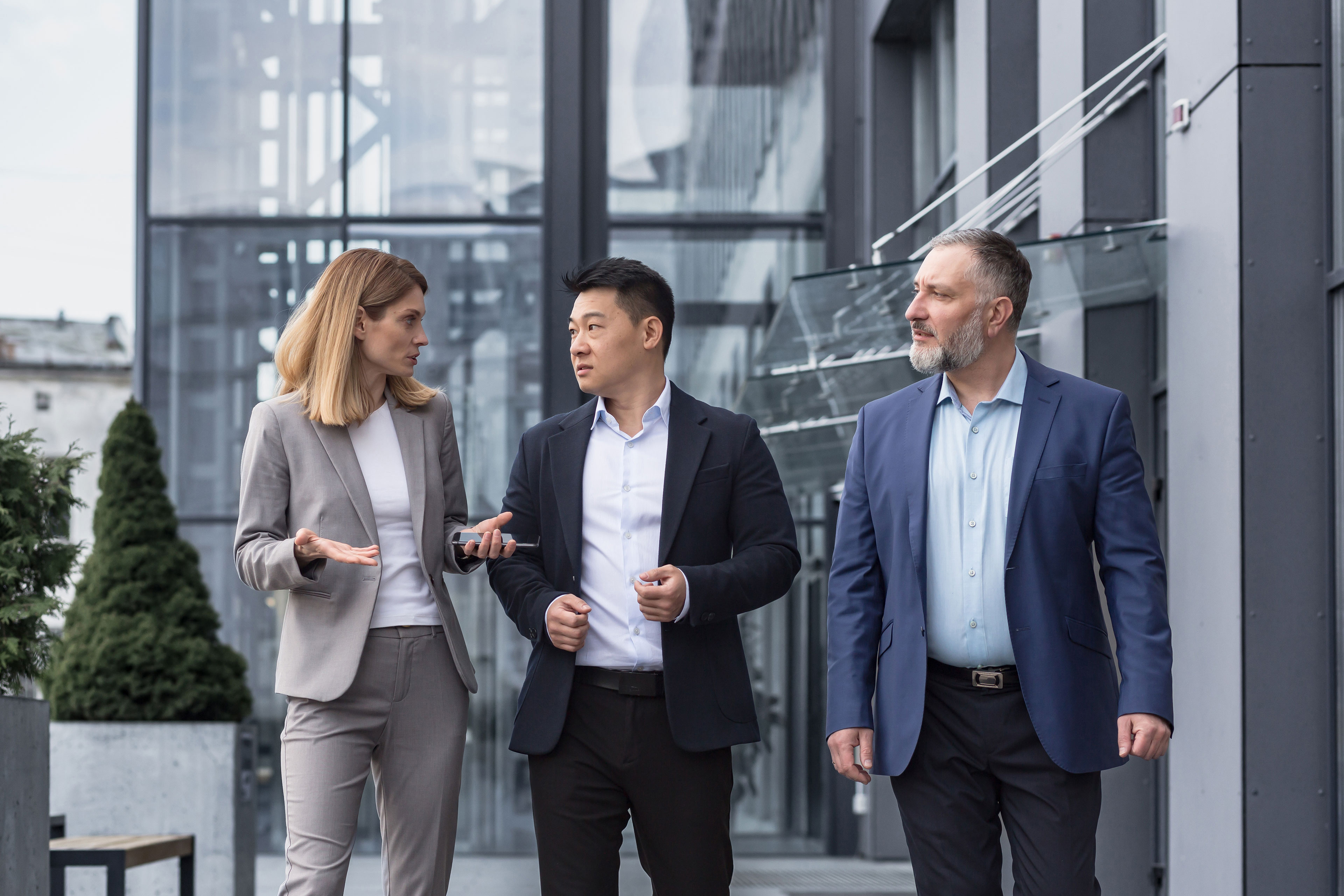 Three business people walking and talking outside office