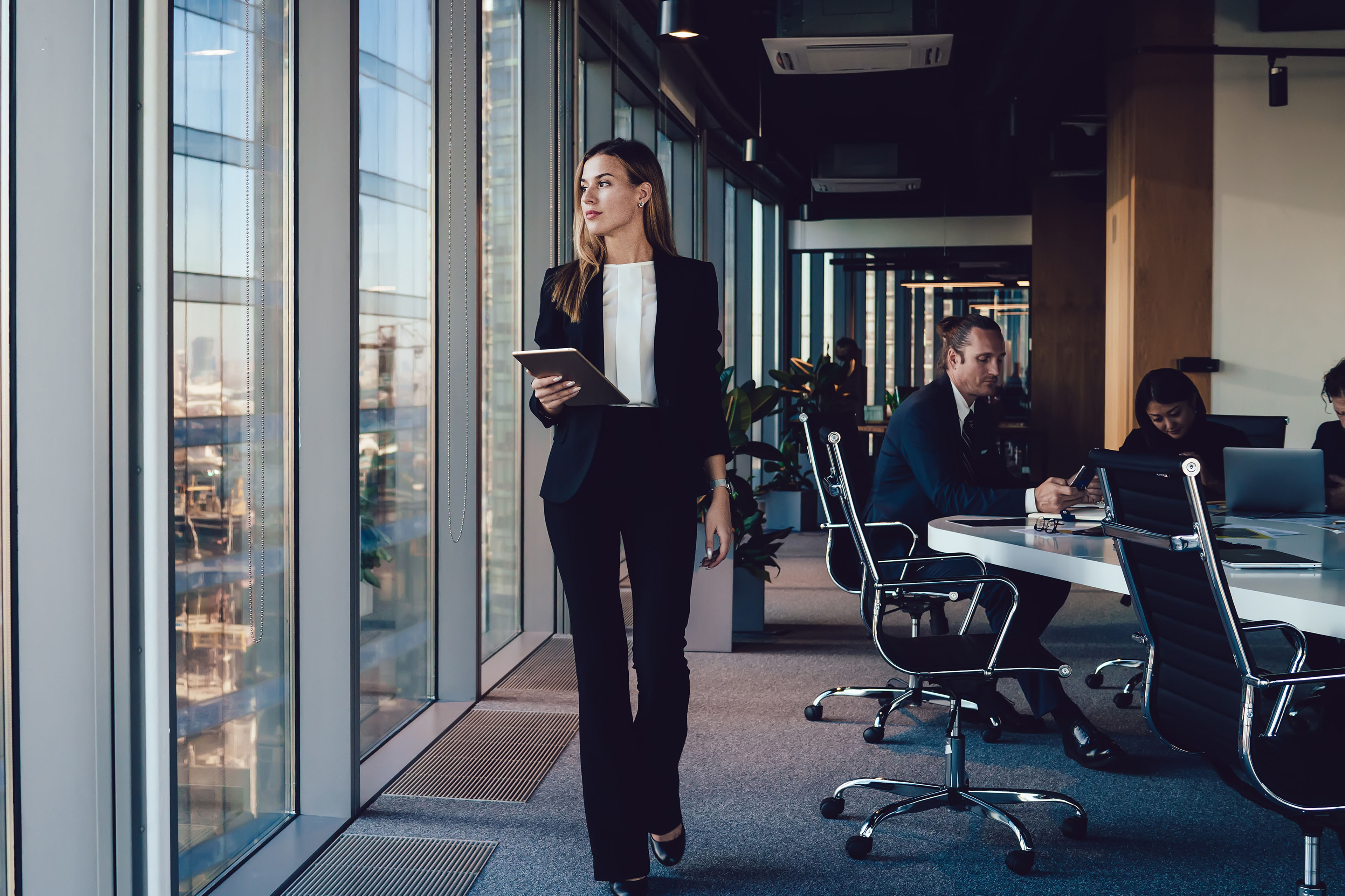 Serious female administrative manager in formal suit walking in office