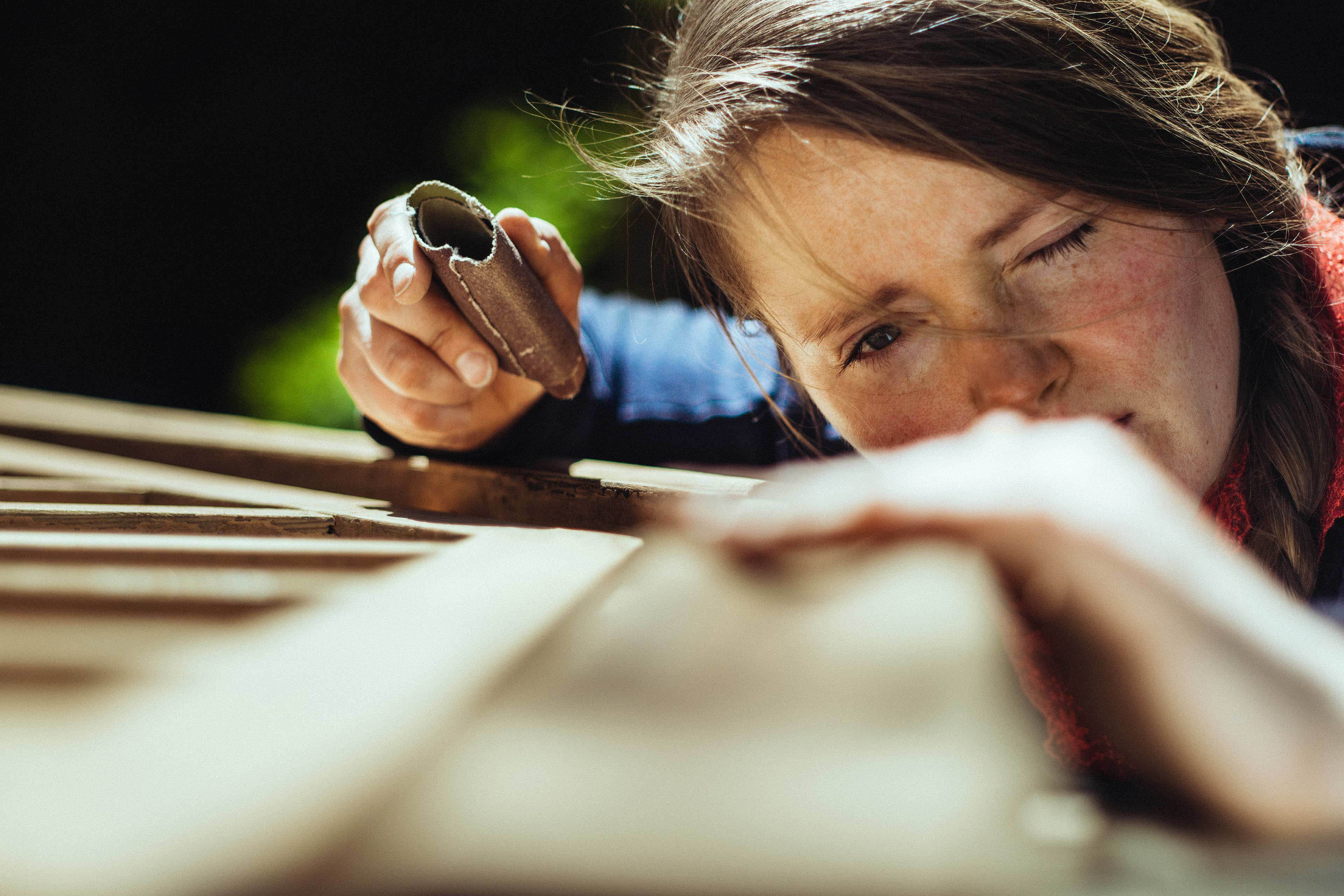 Woman checking her work after grinding an old handrail