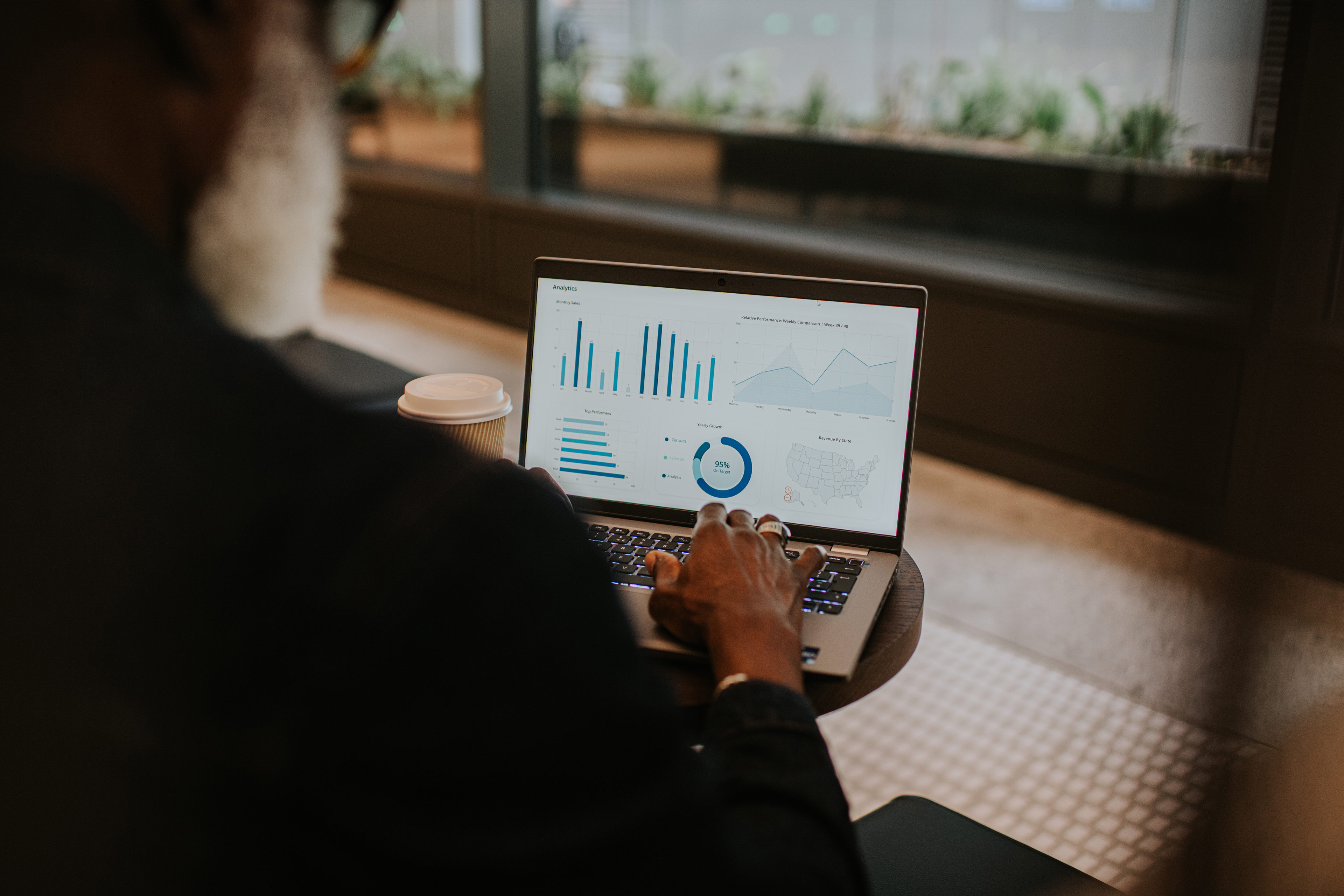 Man focusing on laptop screen displaying graphs and charts