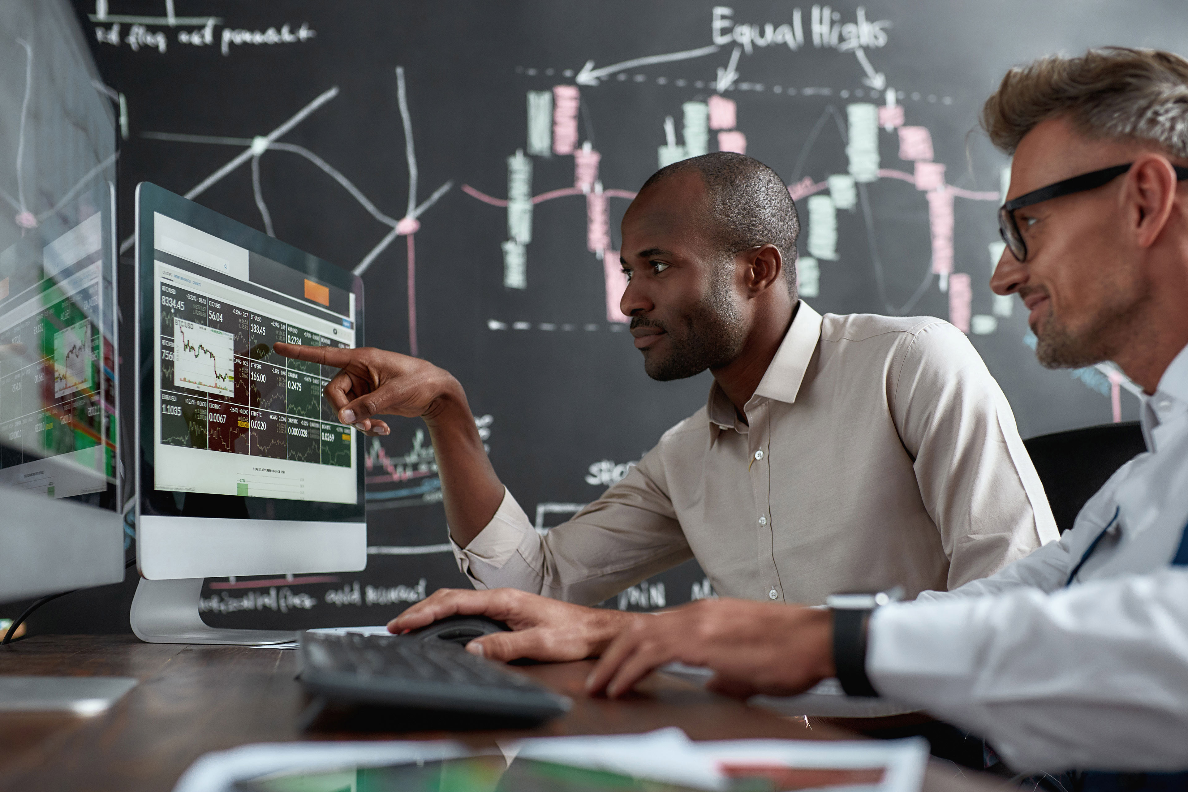 Two men looking at graphs on computer