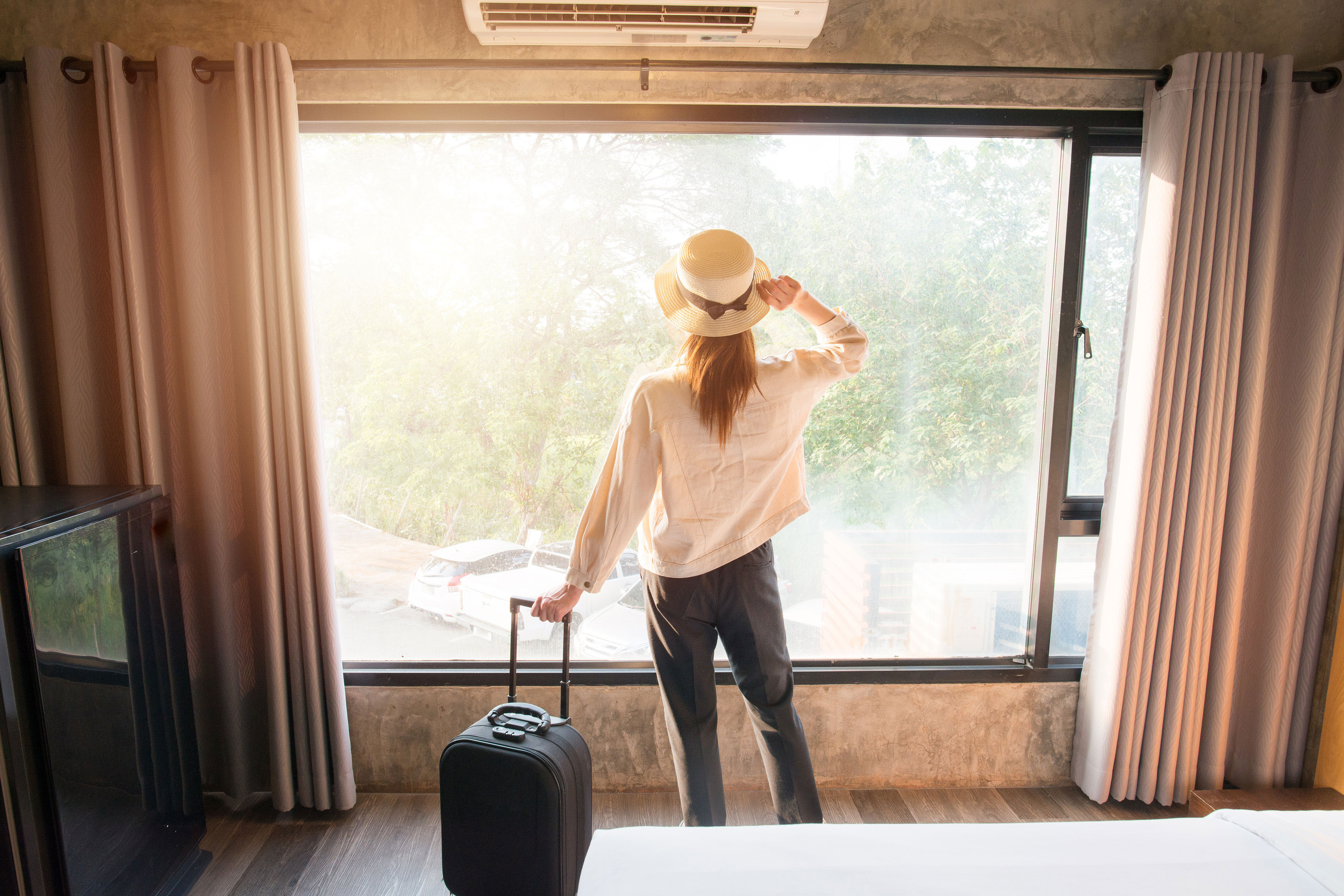 EY woman looking out hotel room