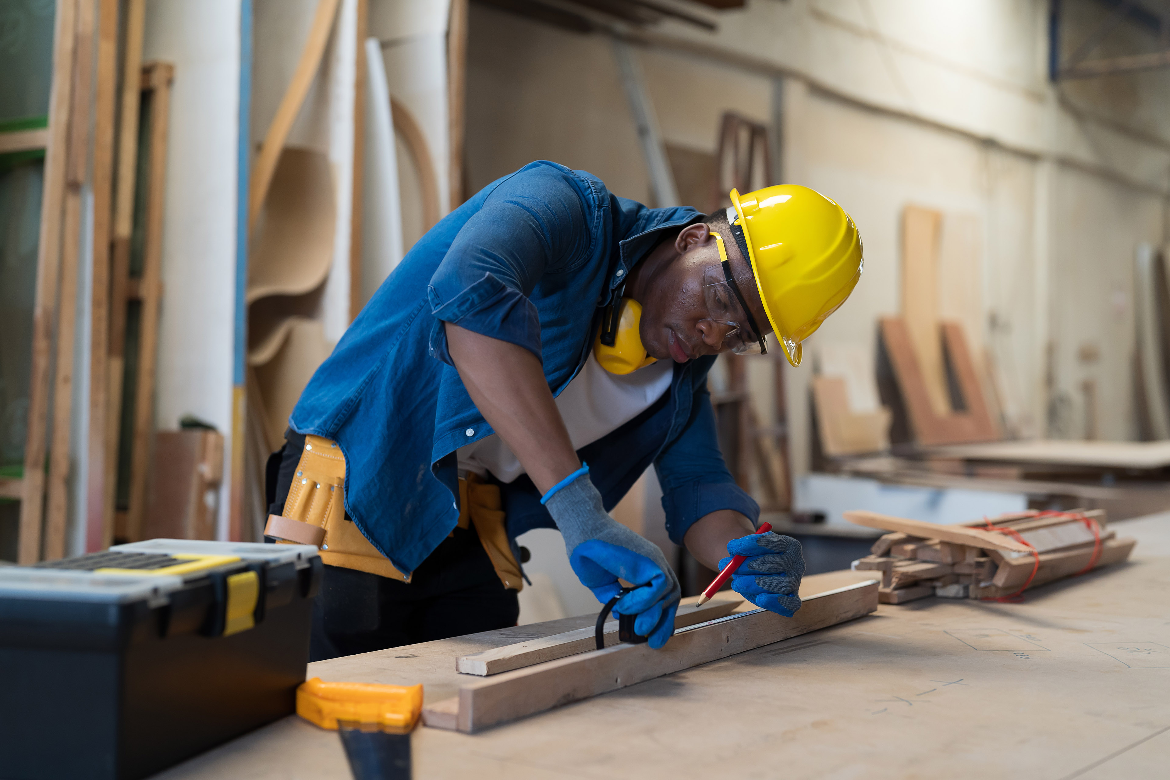 Male carpenter using tape measure piece of wood in wood processing plants