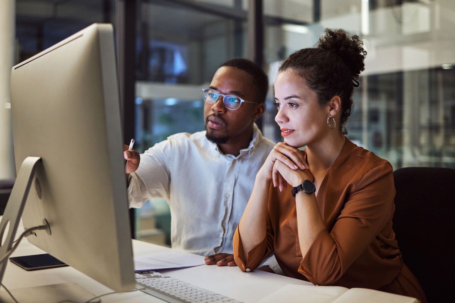 Two colleagues viewing computer late at night