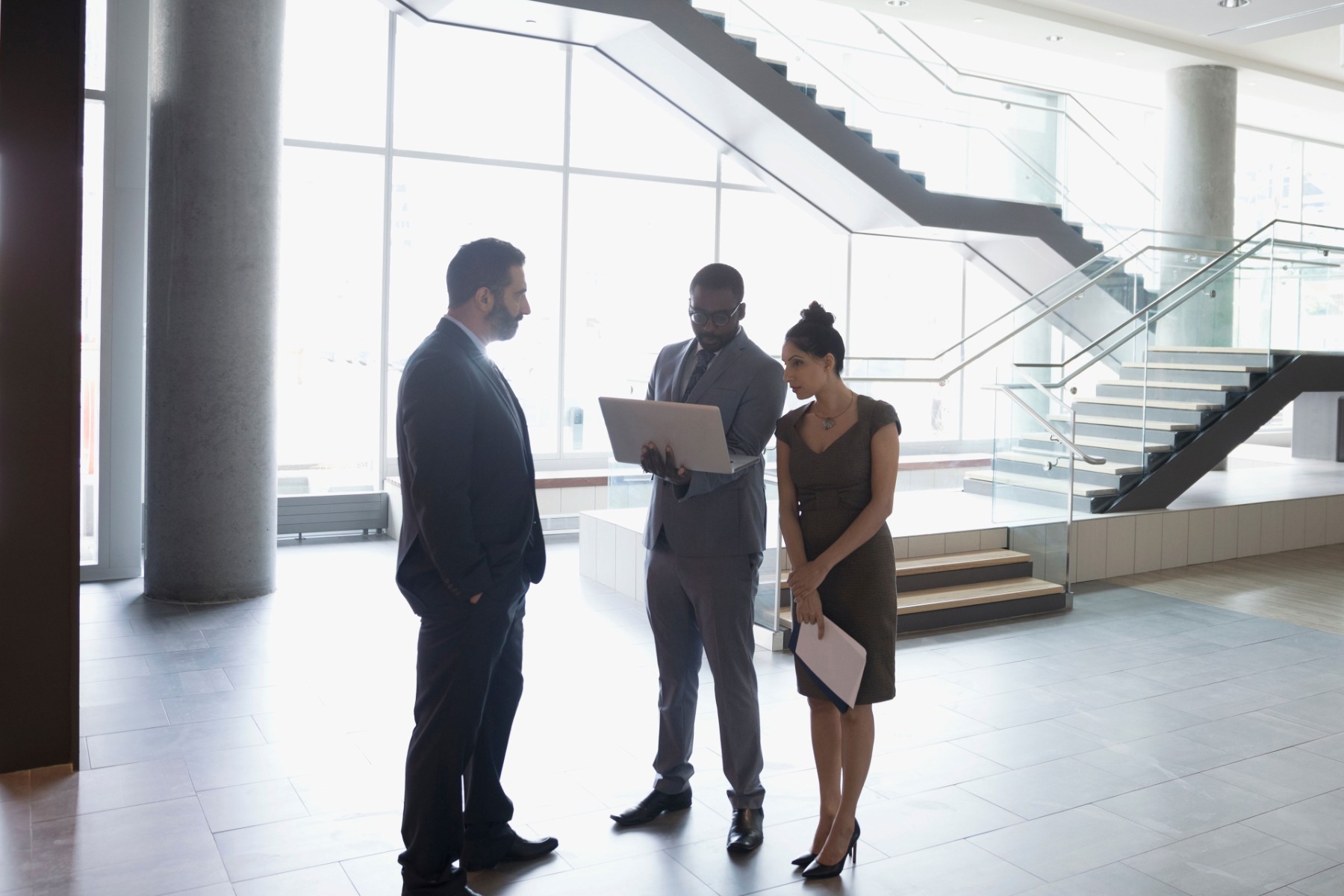 Business people talking with laptop in modern lobby