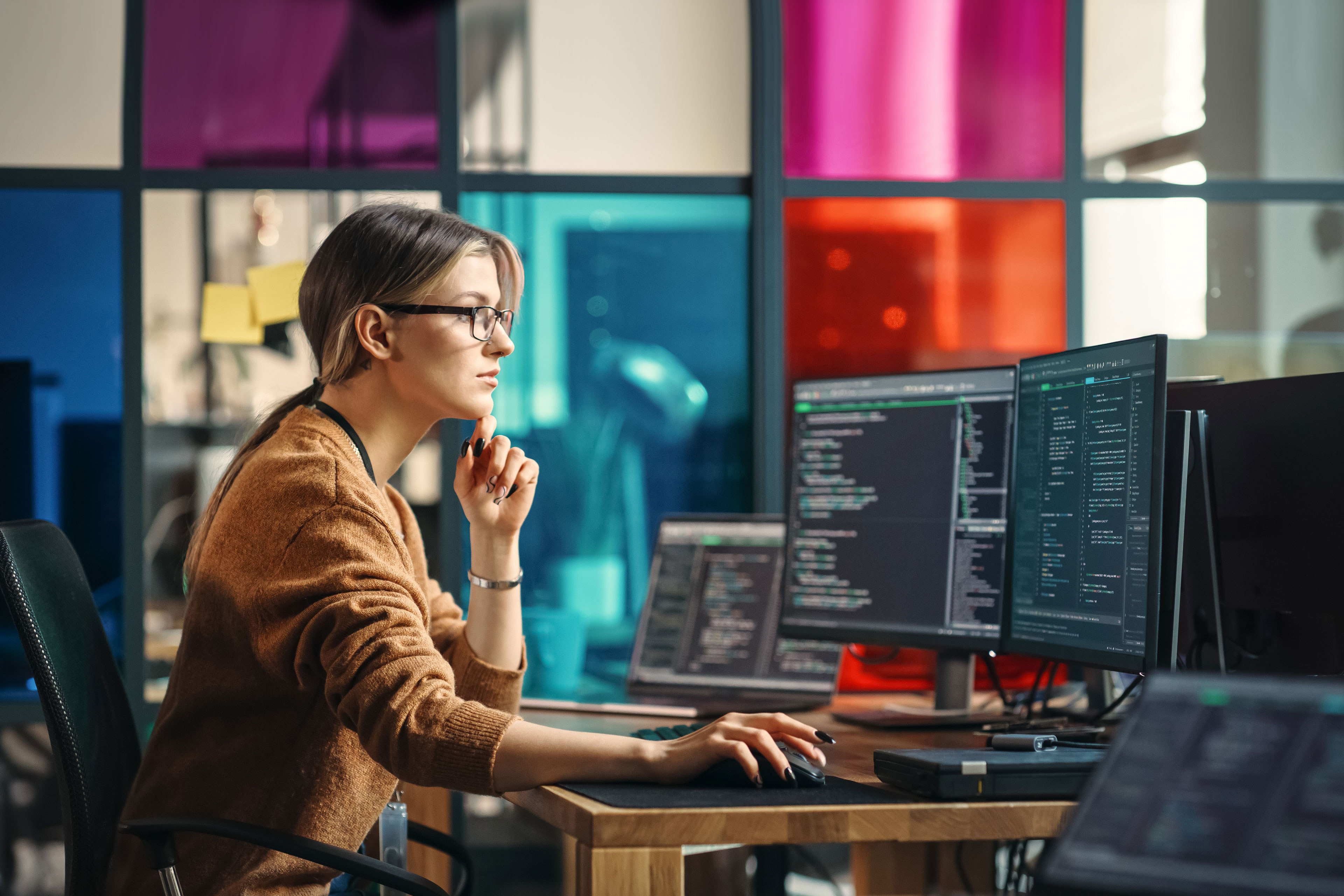 Software engineer writes code with two monitors