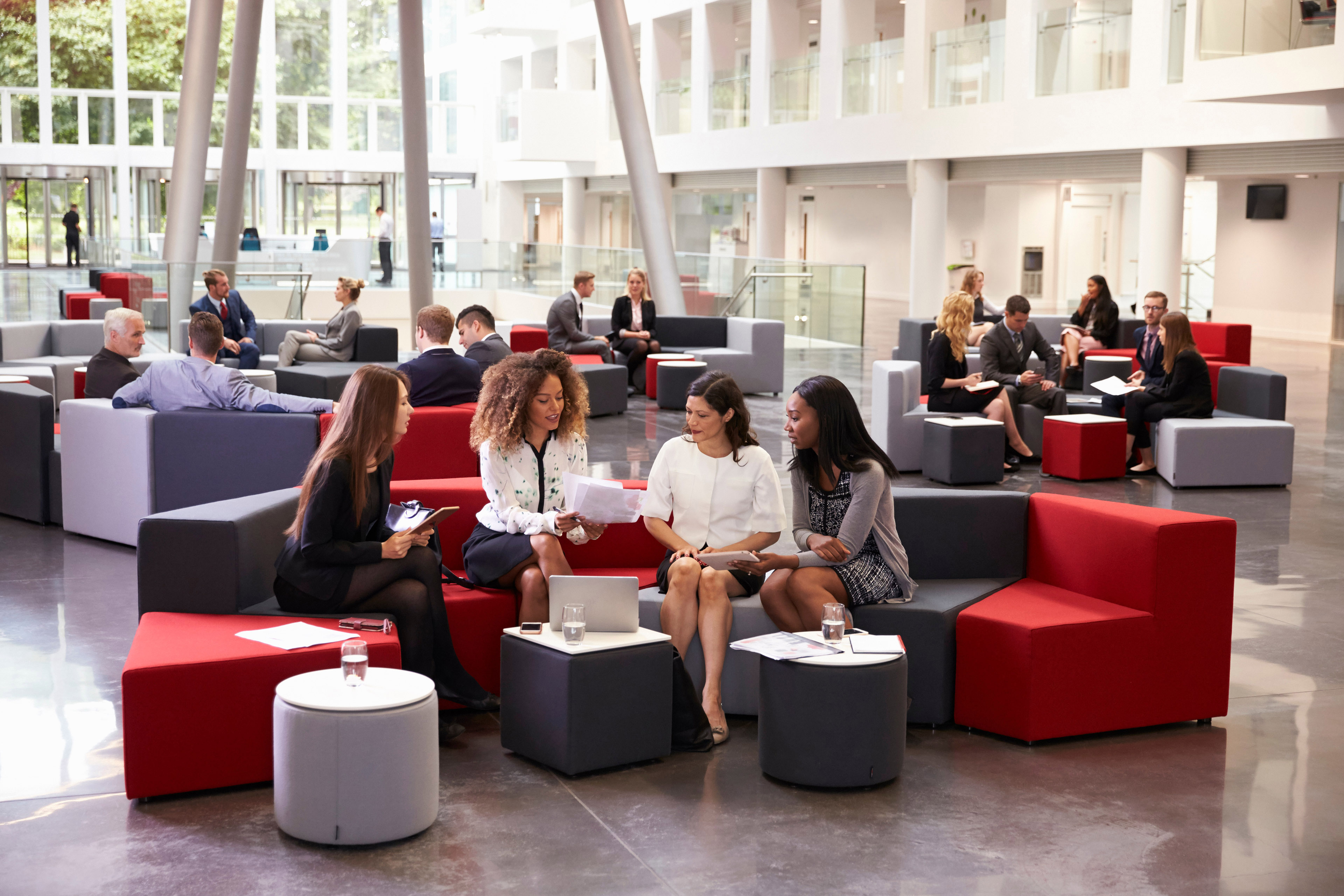 Businesswomen meeting in busy lobby of modern office