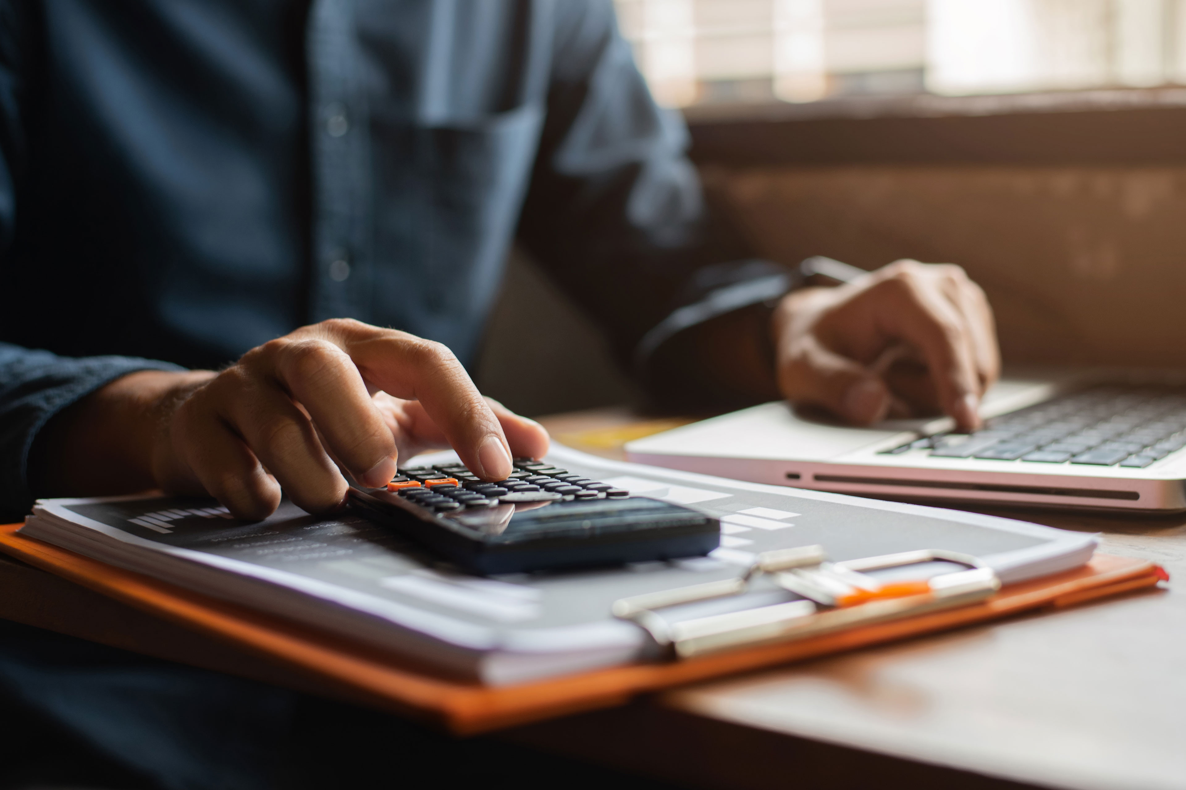 Hand businessman doing finances and calculate on desk about cost at office.