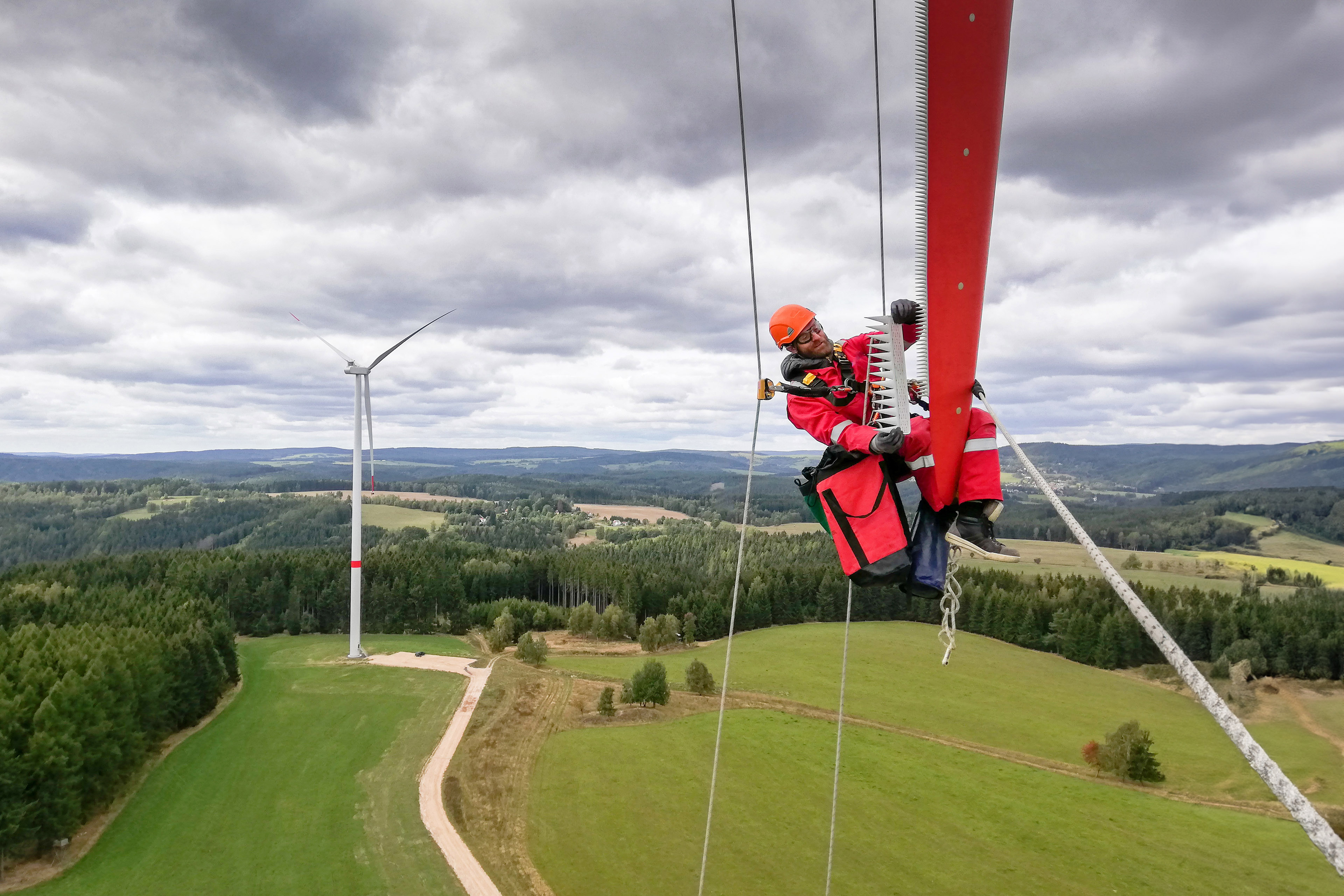 Industrial climber technician working on the wind turbine blade