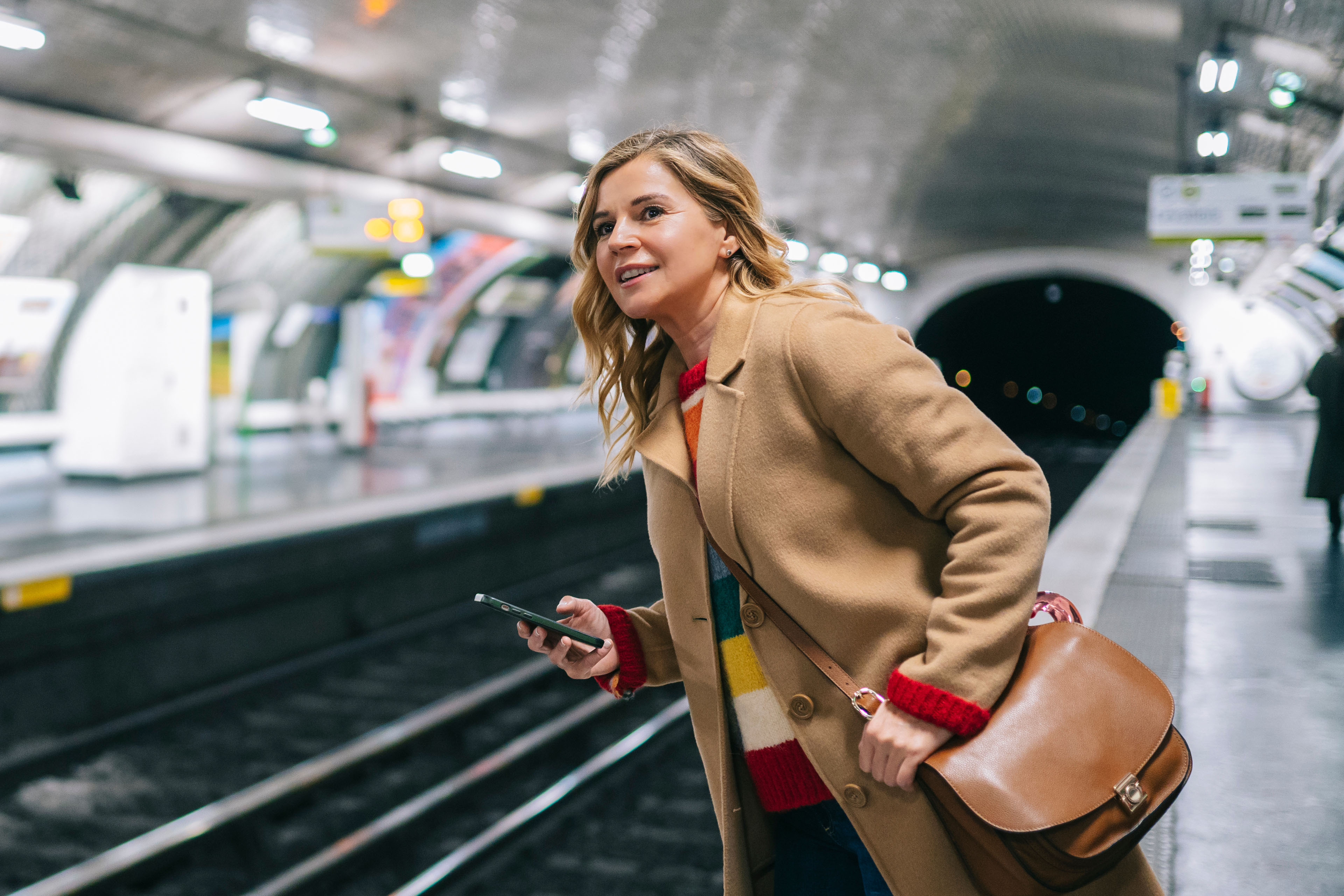 Young lady with smartphone waiting for metro train