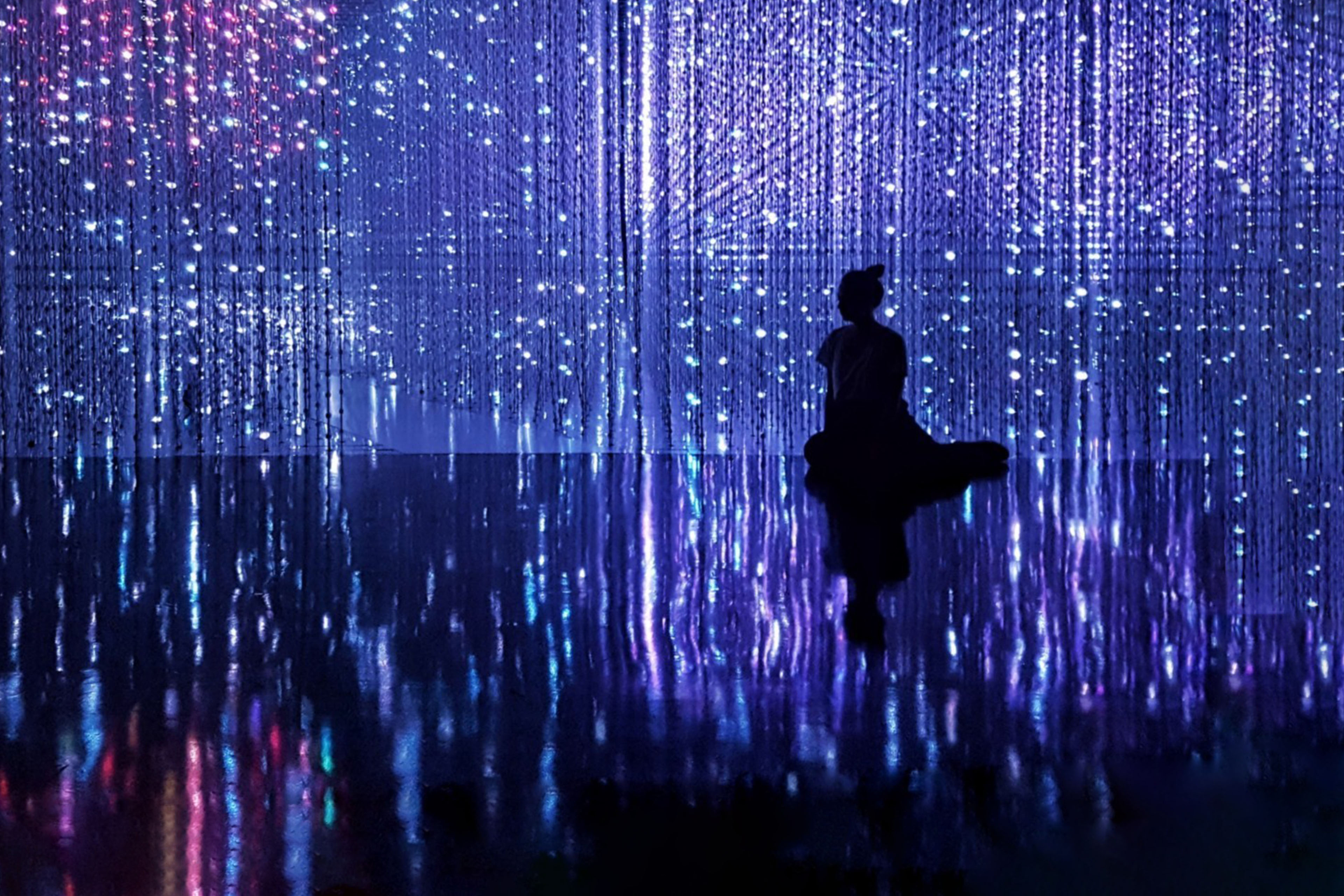 rear-view-of-silhouette-woman-sitting-against-illuminated-decoration