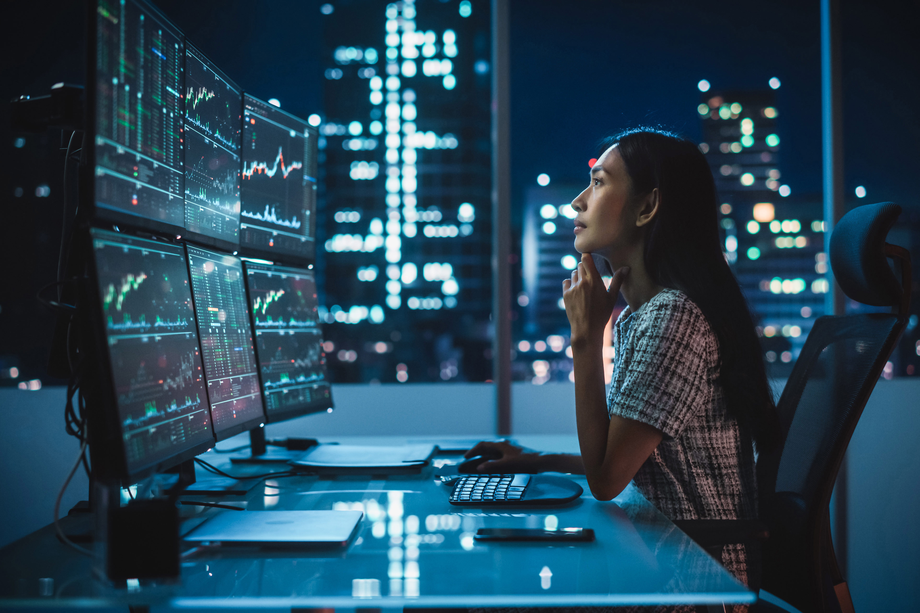 Woman works on data analysis on several computer screens