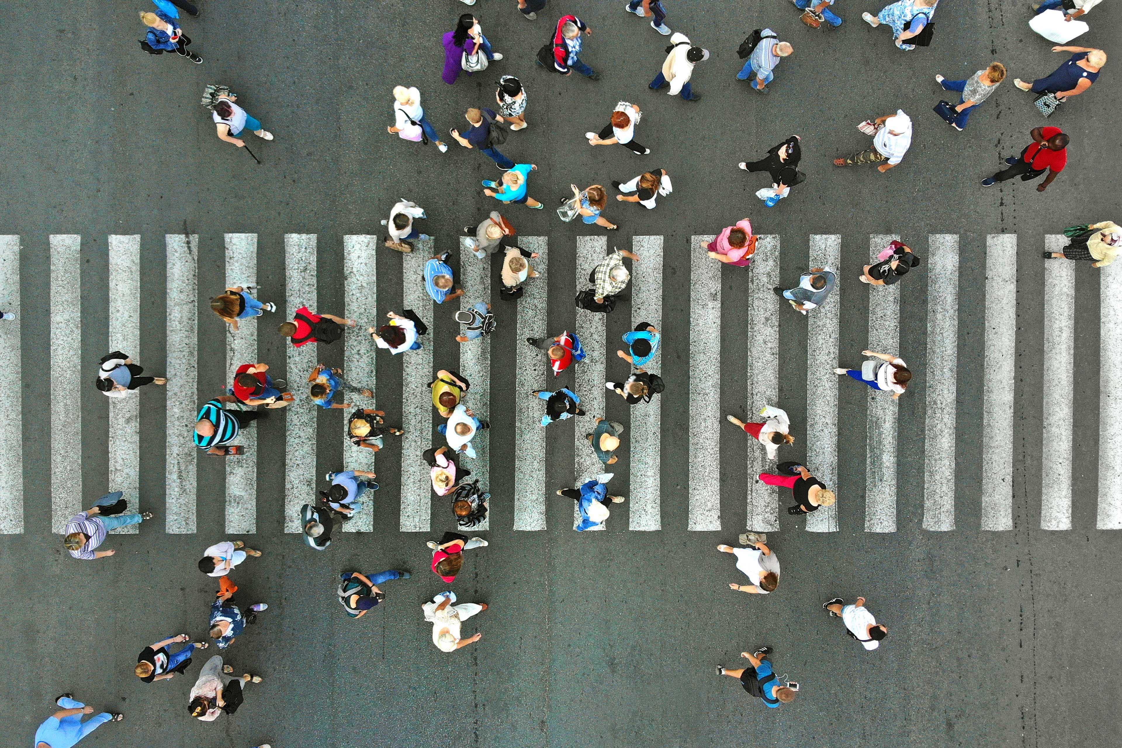 Aerial. Pedestrians passing a crosswalk. Rush hour in the city. People are rushing to work.