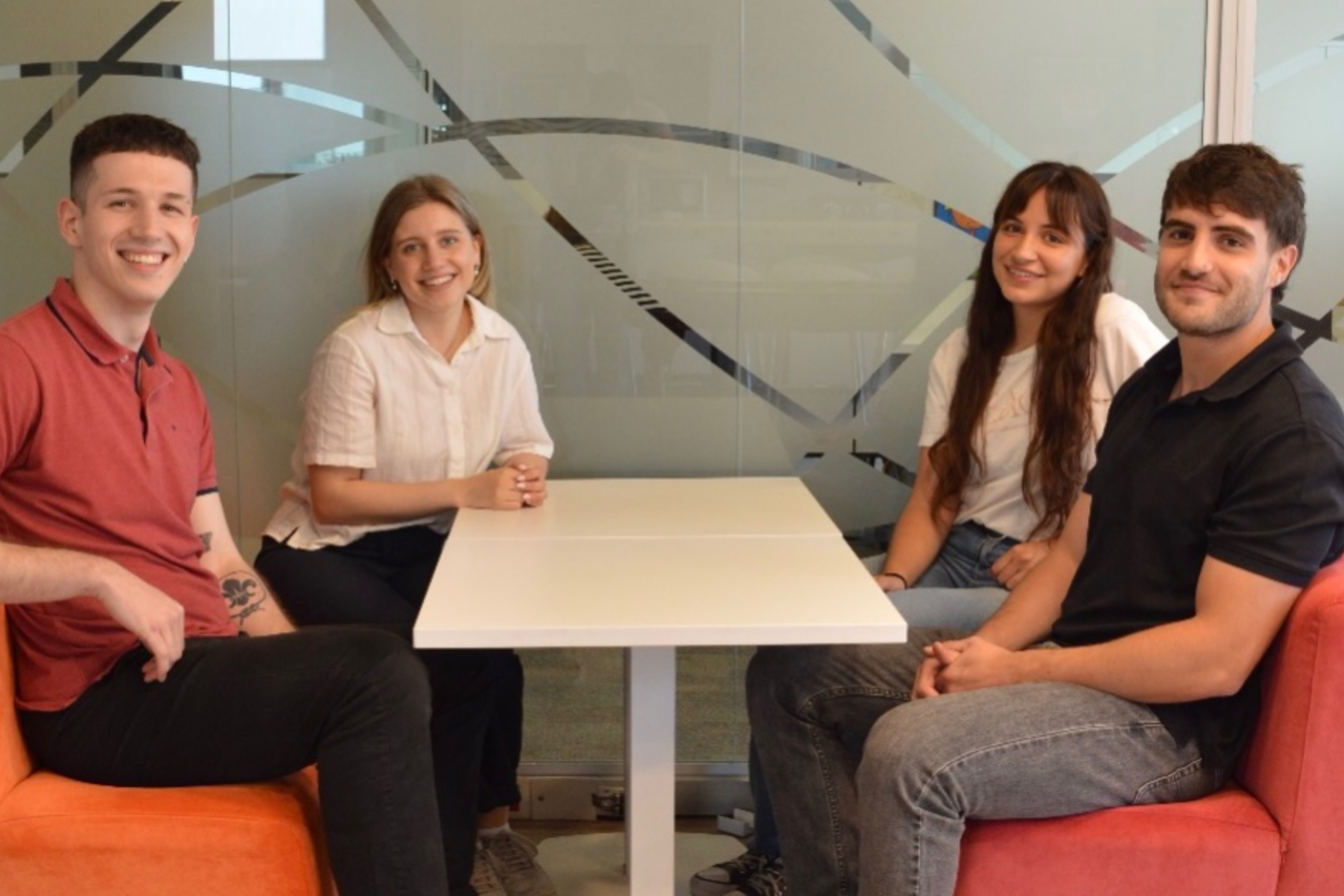 Equipo de cuatro jóvenes sonríe a la cámara