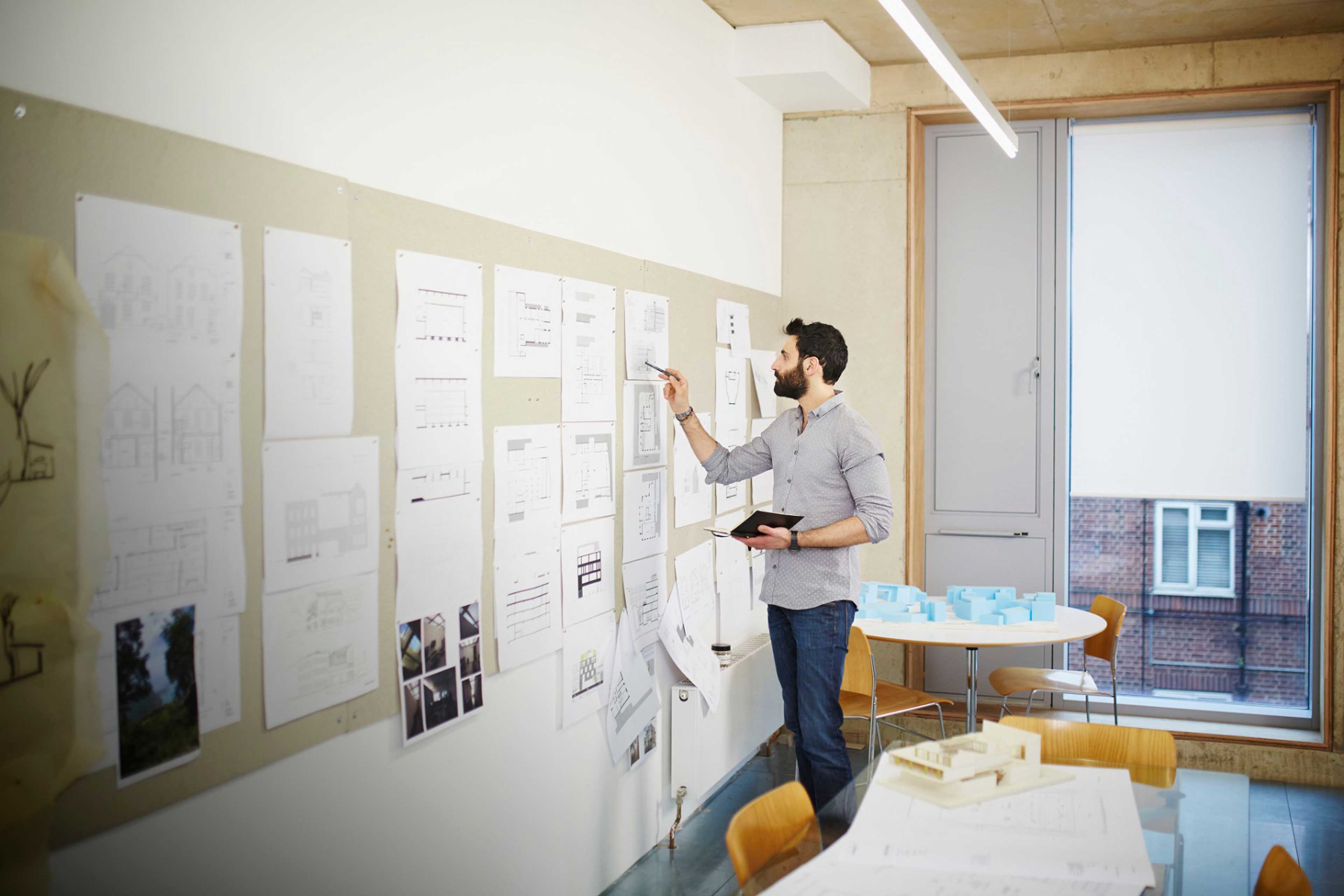 EY architect reviews plans on a pinboard in an office