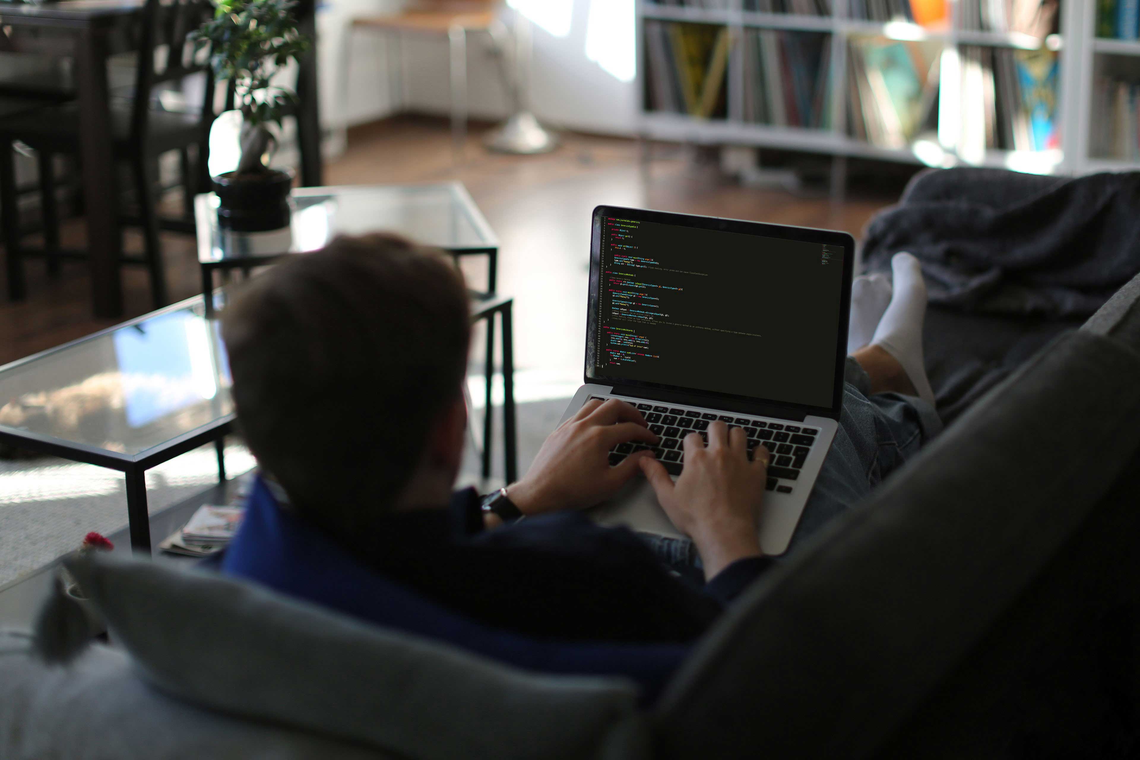 Ey freelancer working from home writing code on sofa