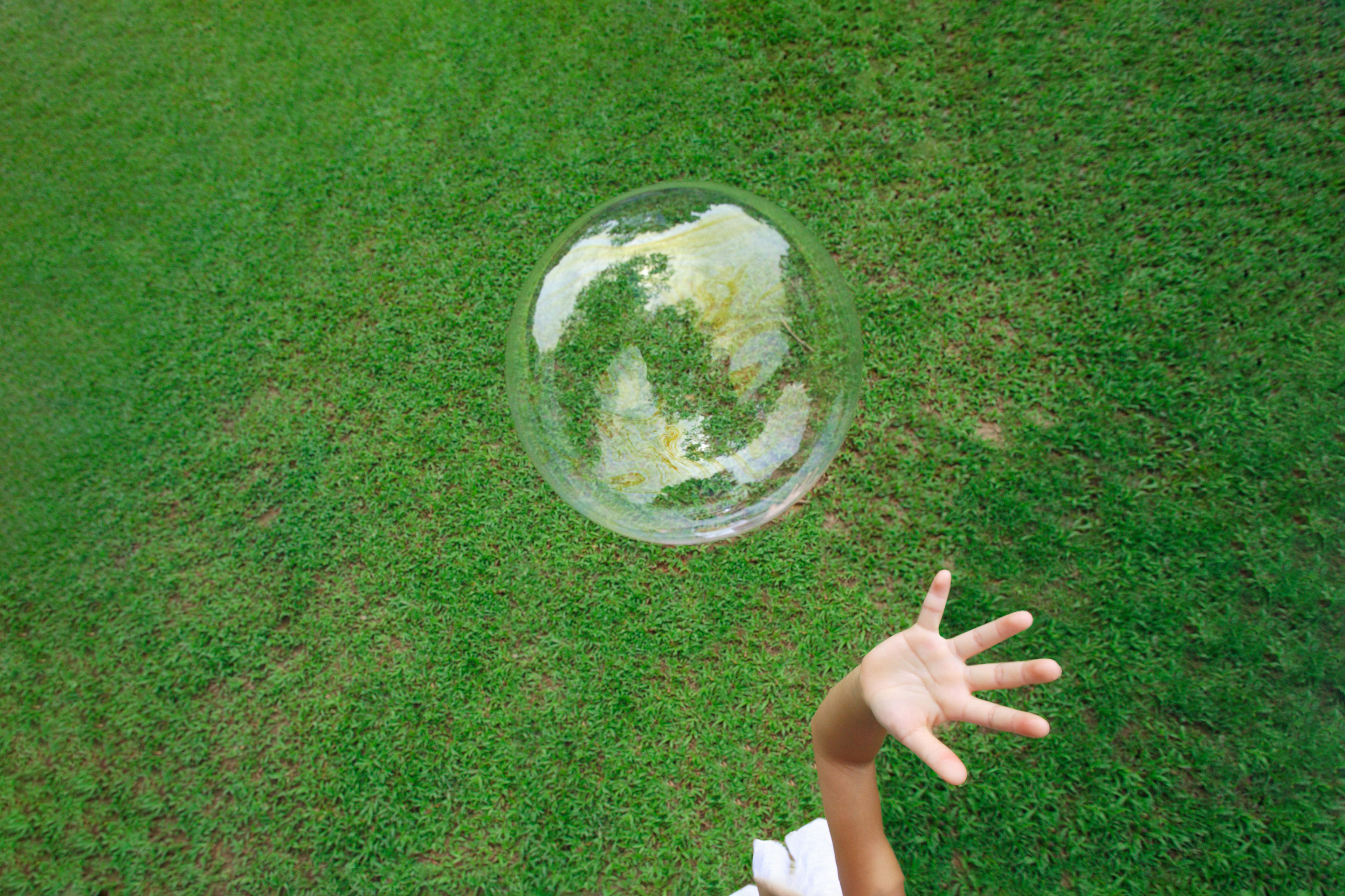 A child playing with soap bubble on grassy field