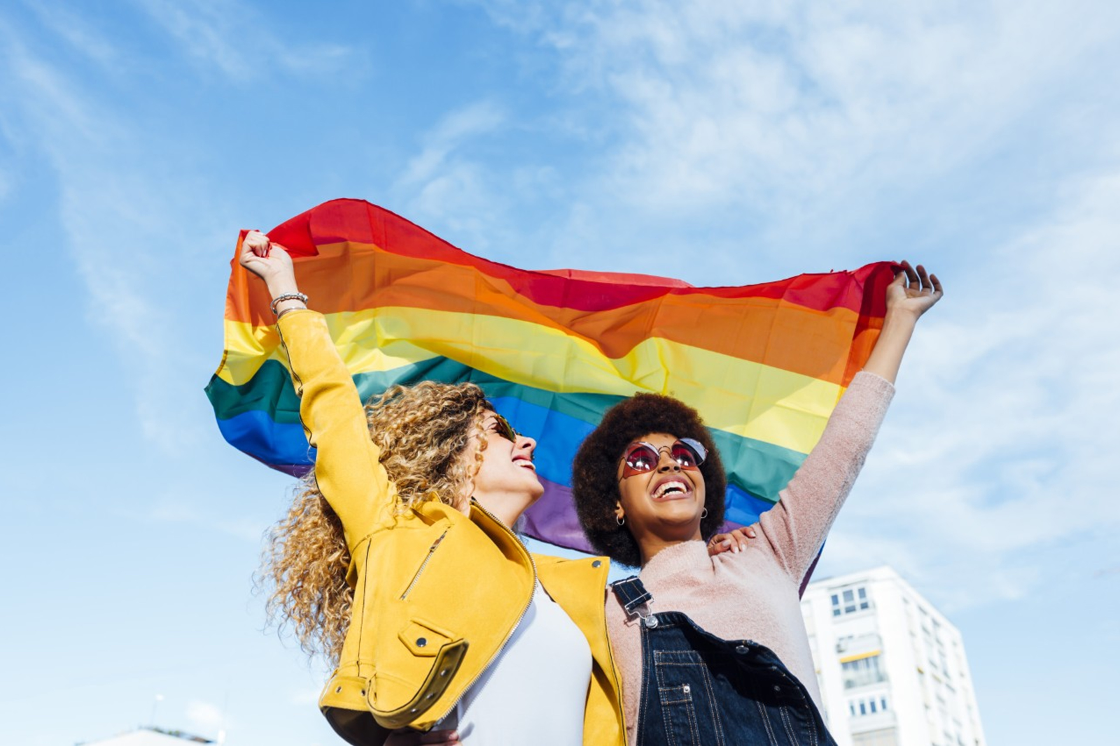 Kaksi iloista naista heiluttamassa Pride lippua