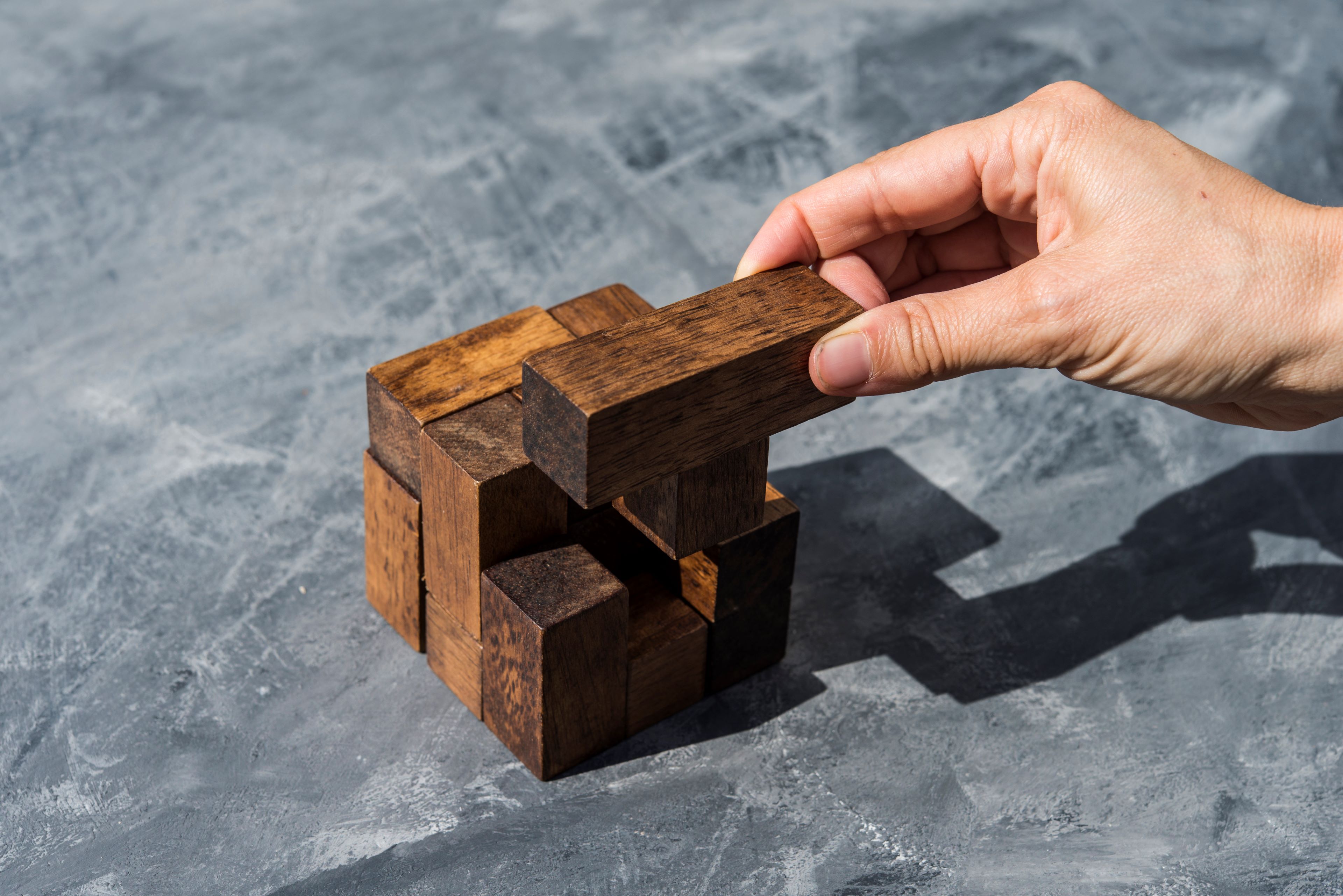 Hand of woman assembling pieces of wooden puzzle