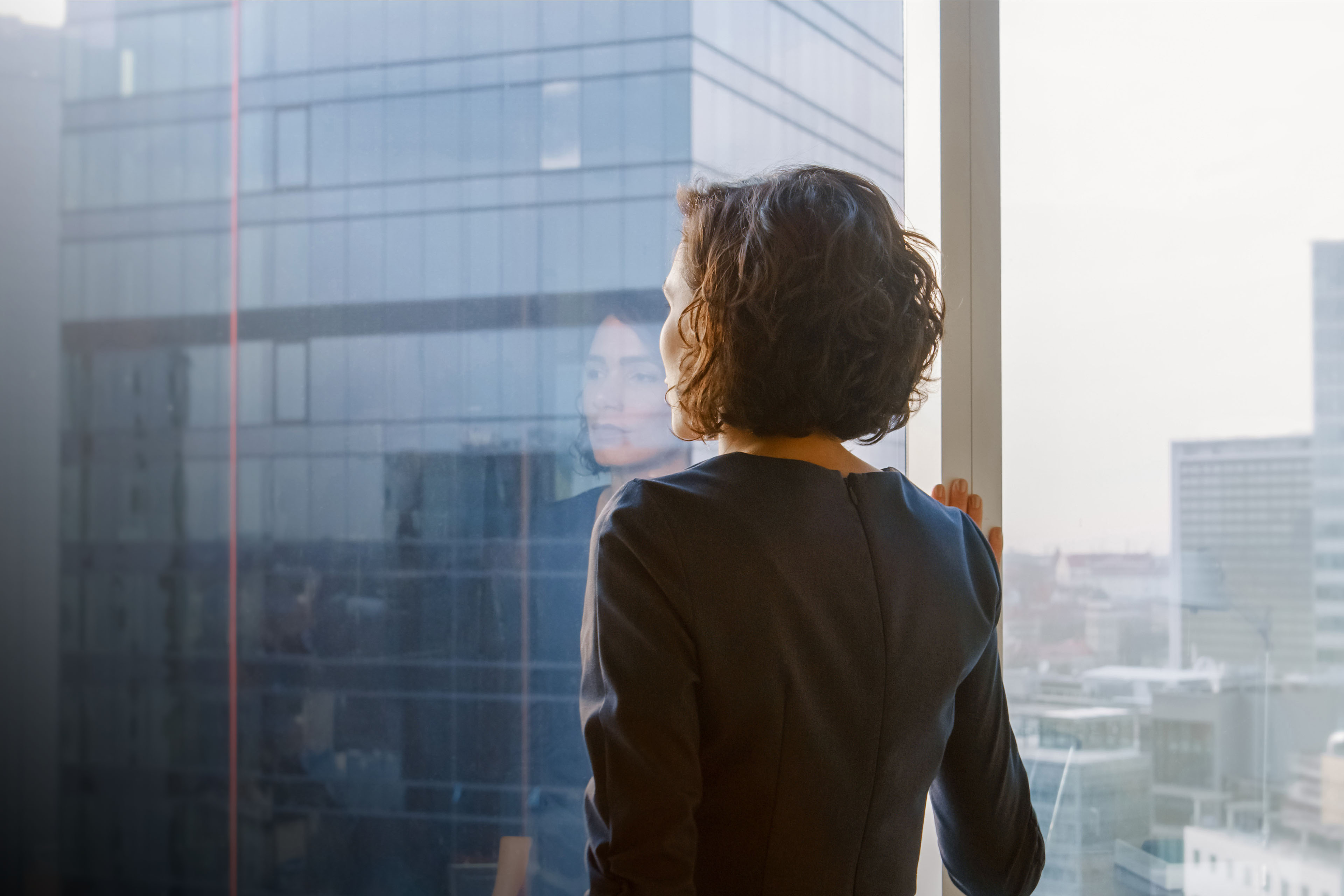 businesswoman looking out of her office window